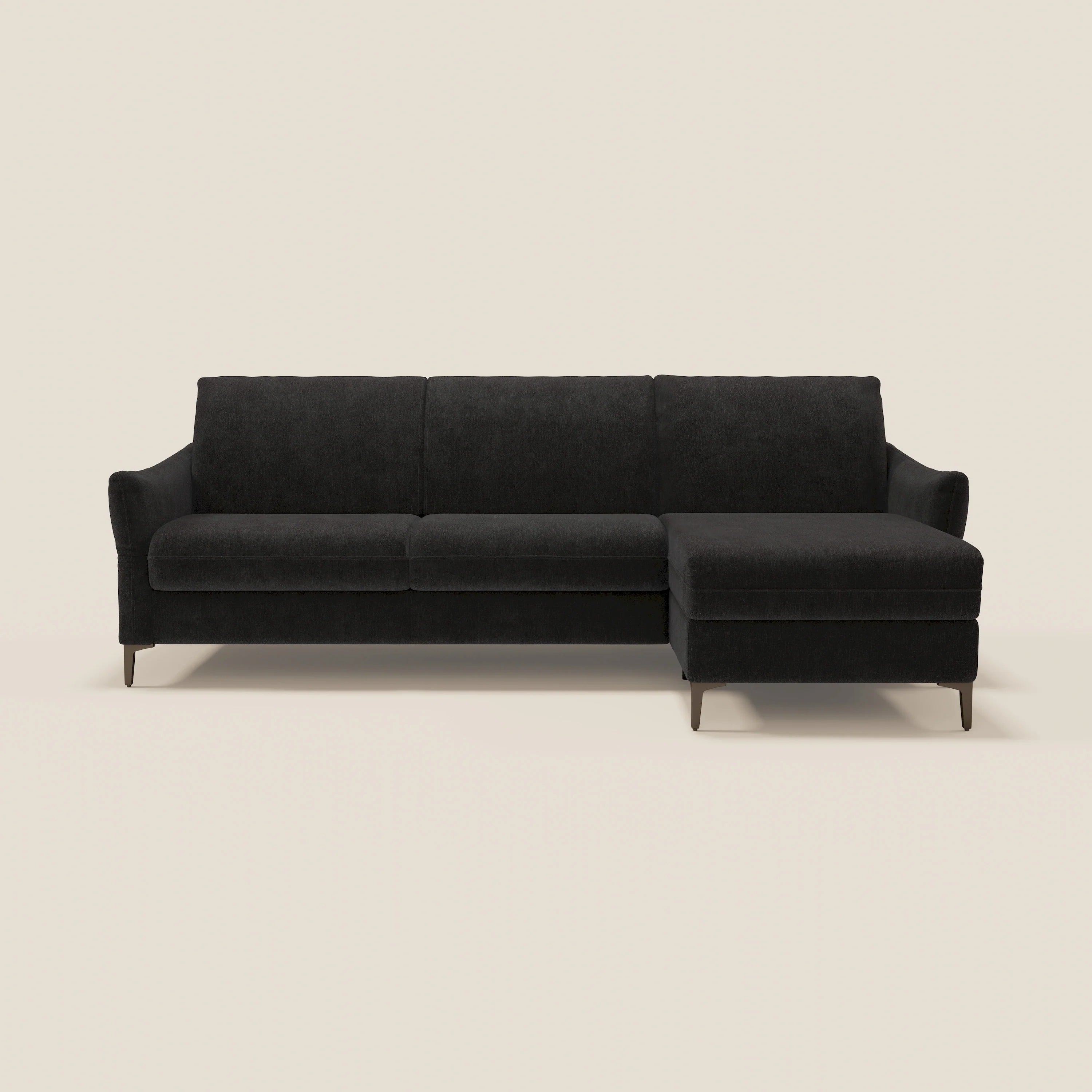 Un moderno divano componibile nero con chaise longue sul lato destro, gambe sottili e braccioli morbidi, su uno sfondo semplice, bianco sporco.