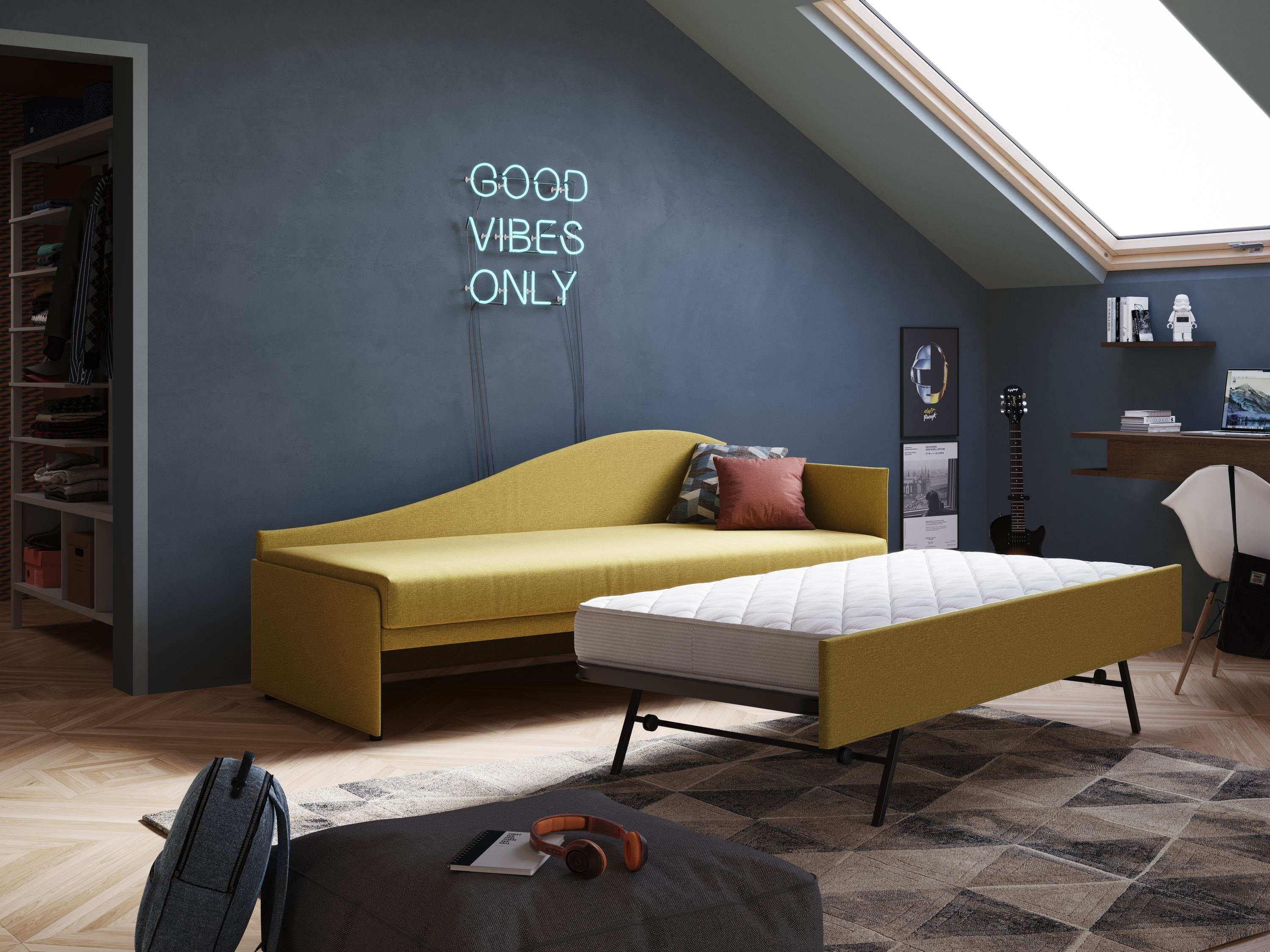 Una moderna camera da letto in mansarda con un daybed giallo parzialmente estraibile come letto a scomparsa, una parete d'accento grigia con una scritta al neon "Good Vibes Only", una scrivania, una chitarra, un lucernario e un tappeto geometrico.