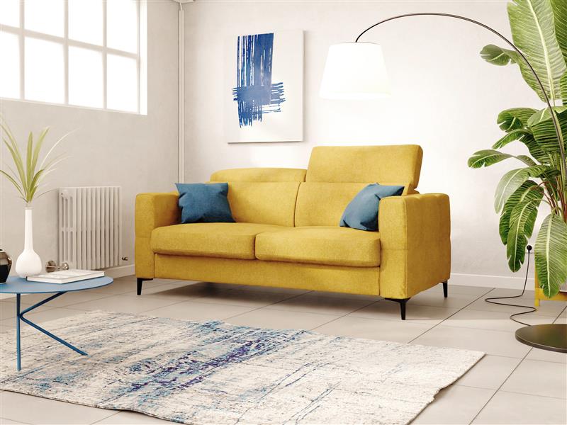 Un soggiorno moderno con un divano giallo, cuscini blu e grigi, una lampada da terra bianca, opere d'arte astratte, una pianta, un tavolino da caffè e un tappeto leggero e strutturato su un pavimento piastrellato bianco.