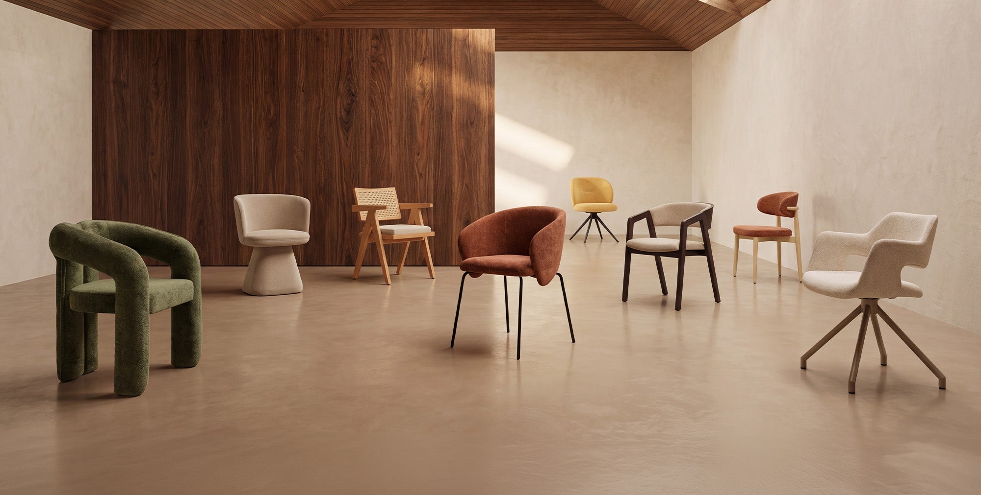 Otto sedie moderne, di vari colori e stili, sono disposte in una stanza spaziosa con pareti beige, una parete d’accento in legno e un pavimento chiaro e lucido, sotto un soffitto spiovente in legno.