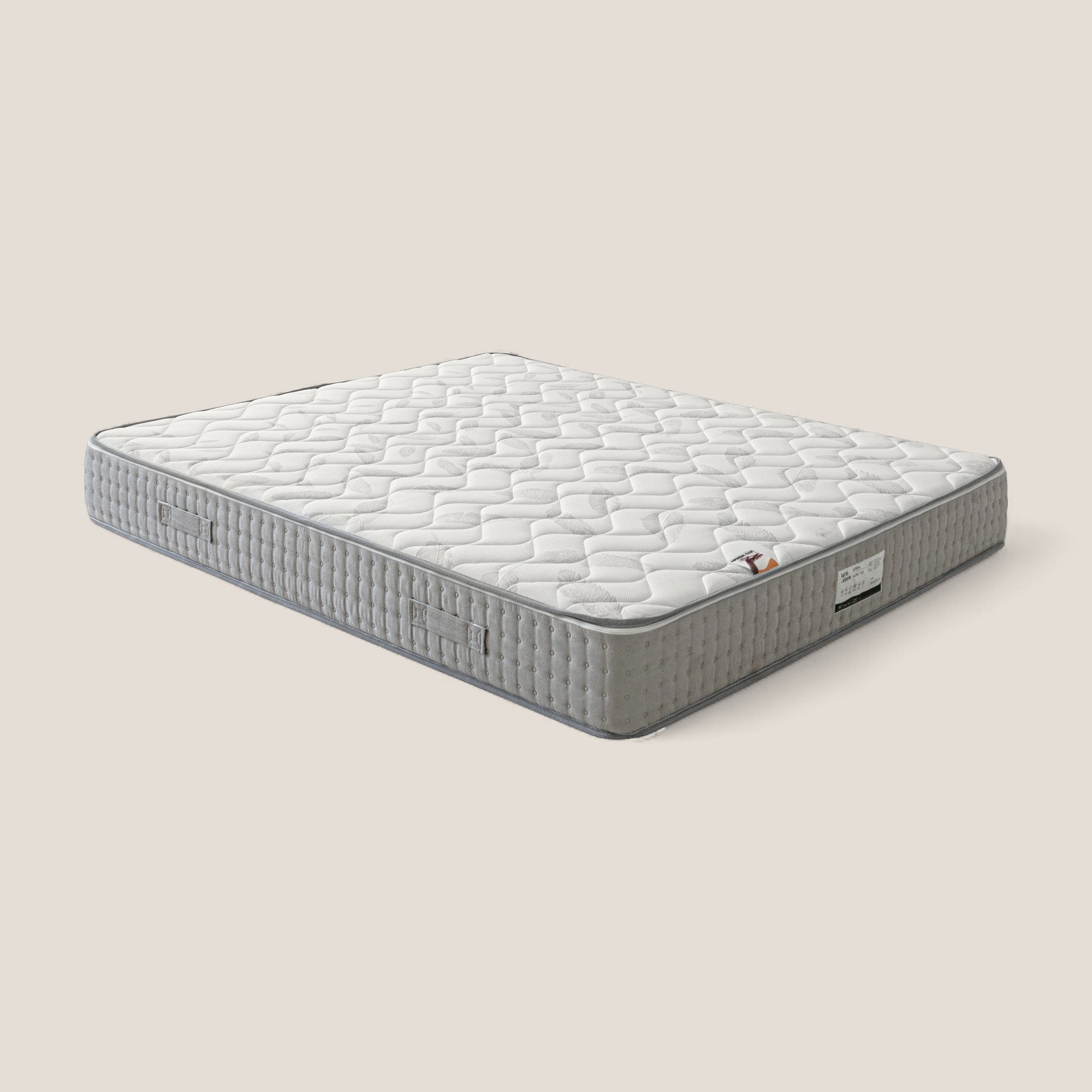 Il Materasso Ortopedico AERION di Divani.Store in Memory & Aquapur ha il piano trapuntato bianco, i lati strutturati grigio chiaro con maniglie, una piccola etichetta angolare e offre un comfort di medio profilo su uno sfondo beige chiaro.