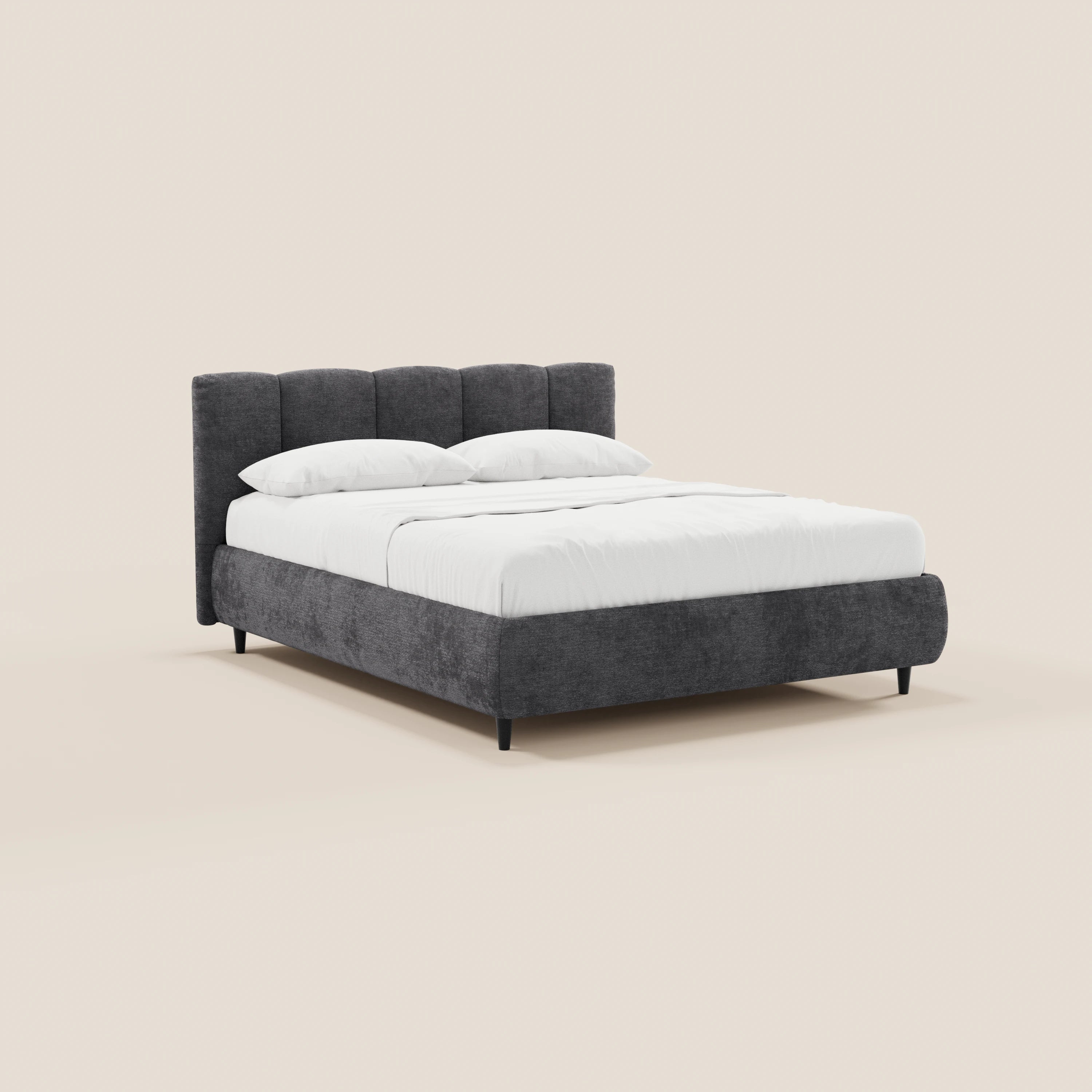 Il letto imbottito ARKAM di Letti.store presenta un design shabby chic con testiera cucita verticalmente, tessuto certificato Oeko-Tex® e un ampio spazio contenitivo. Il letto poggia su corte gambe nere ed è abbinato a biancheria da letto bianca e due cuscini su uno sfondo chiaro.