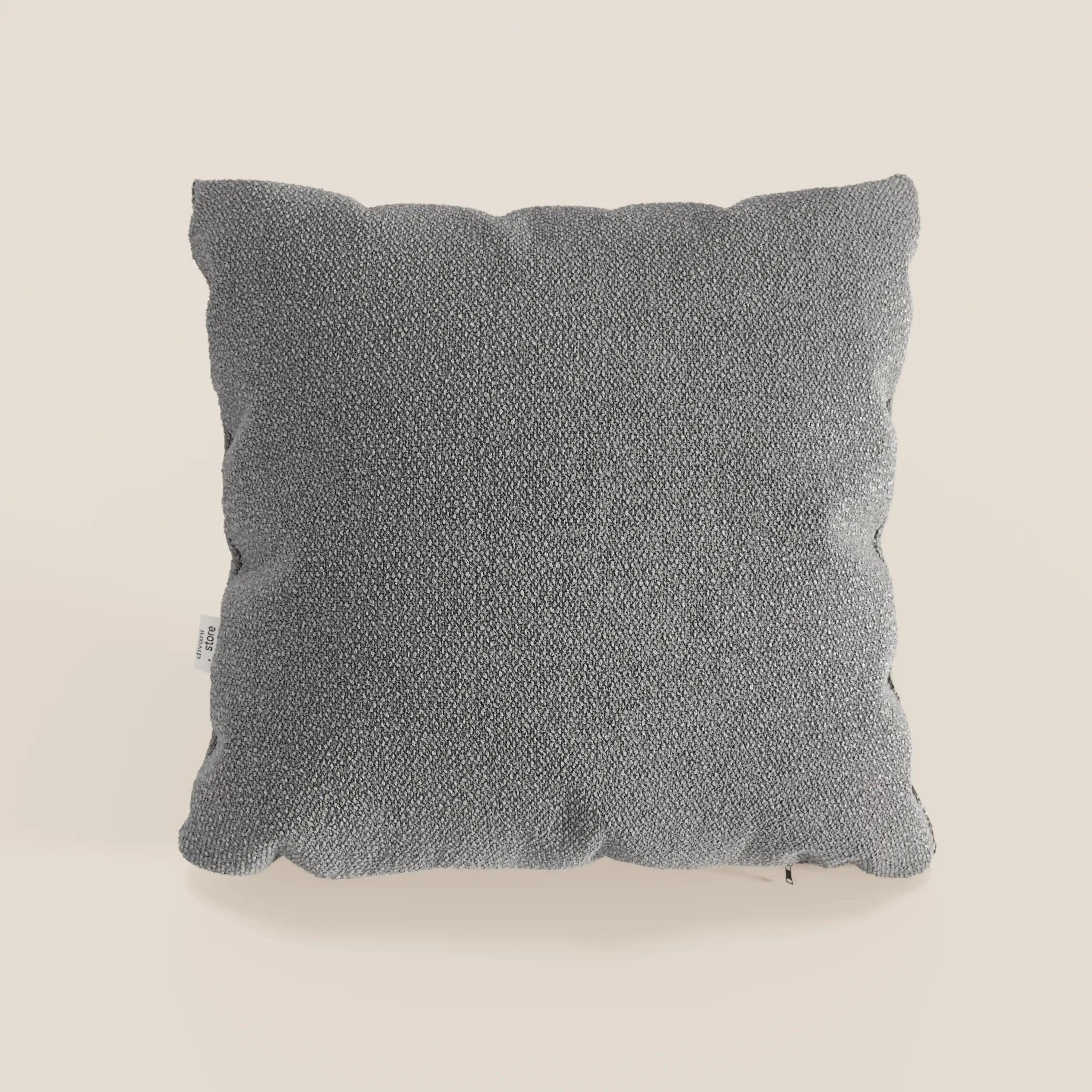 Il cuscino Lambada di Divani.Store, qui presentato in grigio medio, è caratterizzato da un rivestimento quadrato e strutturato in tessuto fresco, antimacchia e impermeabile tipo cotone T33. Ha angoli delicatamente arrotondati e una piccola etichetta bianca sulla cucitura sinistra.