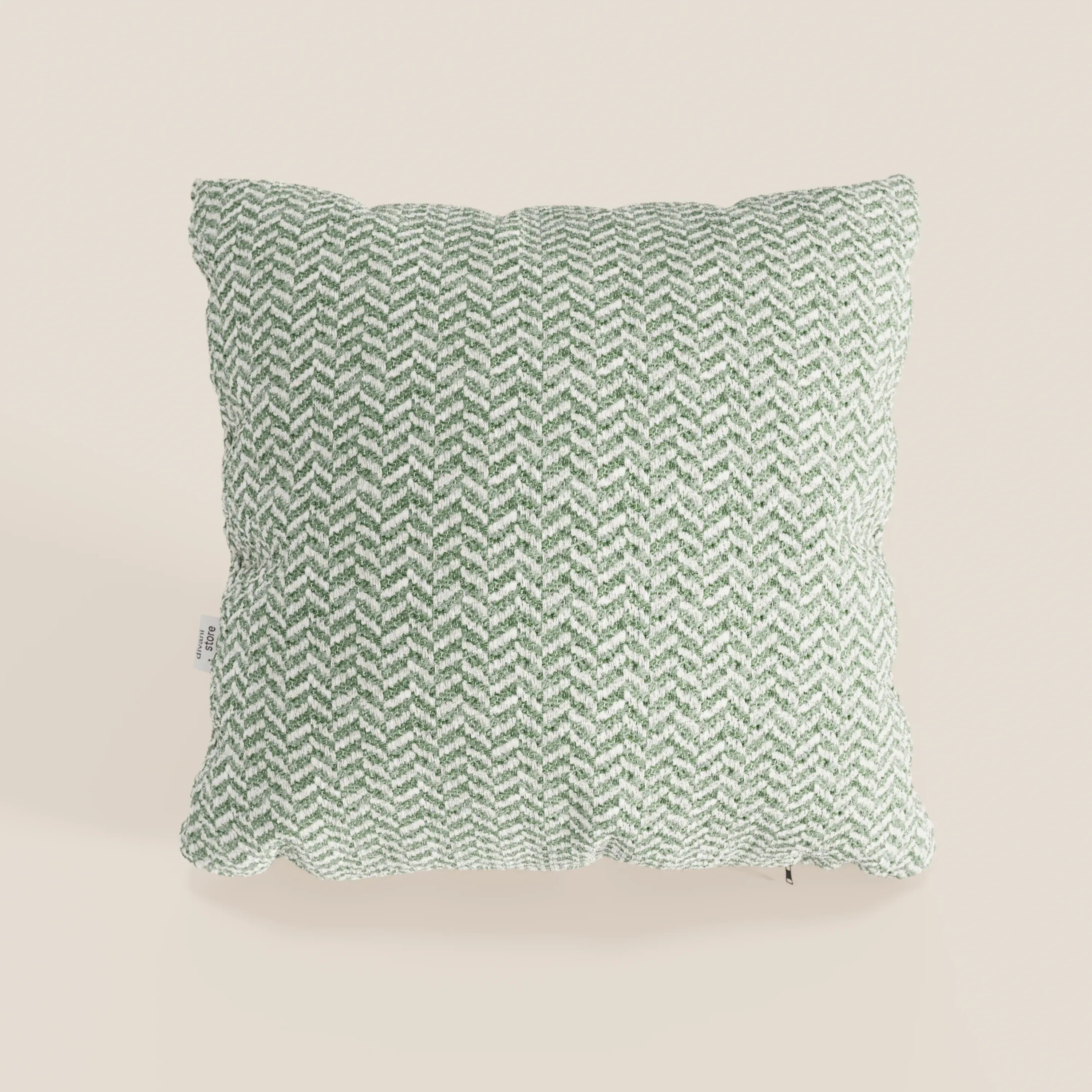 Il cuscino Sorrento 45x45 in lino di Divani.Store è un morbido cuscino quadrato in lino beige chiaro, con un motivo a spina di pesce verde e bianco e una piccola etichetta in tessuto, parte della collezione Eleganza Naturale.