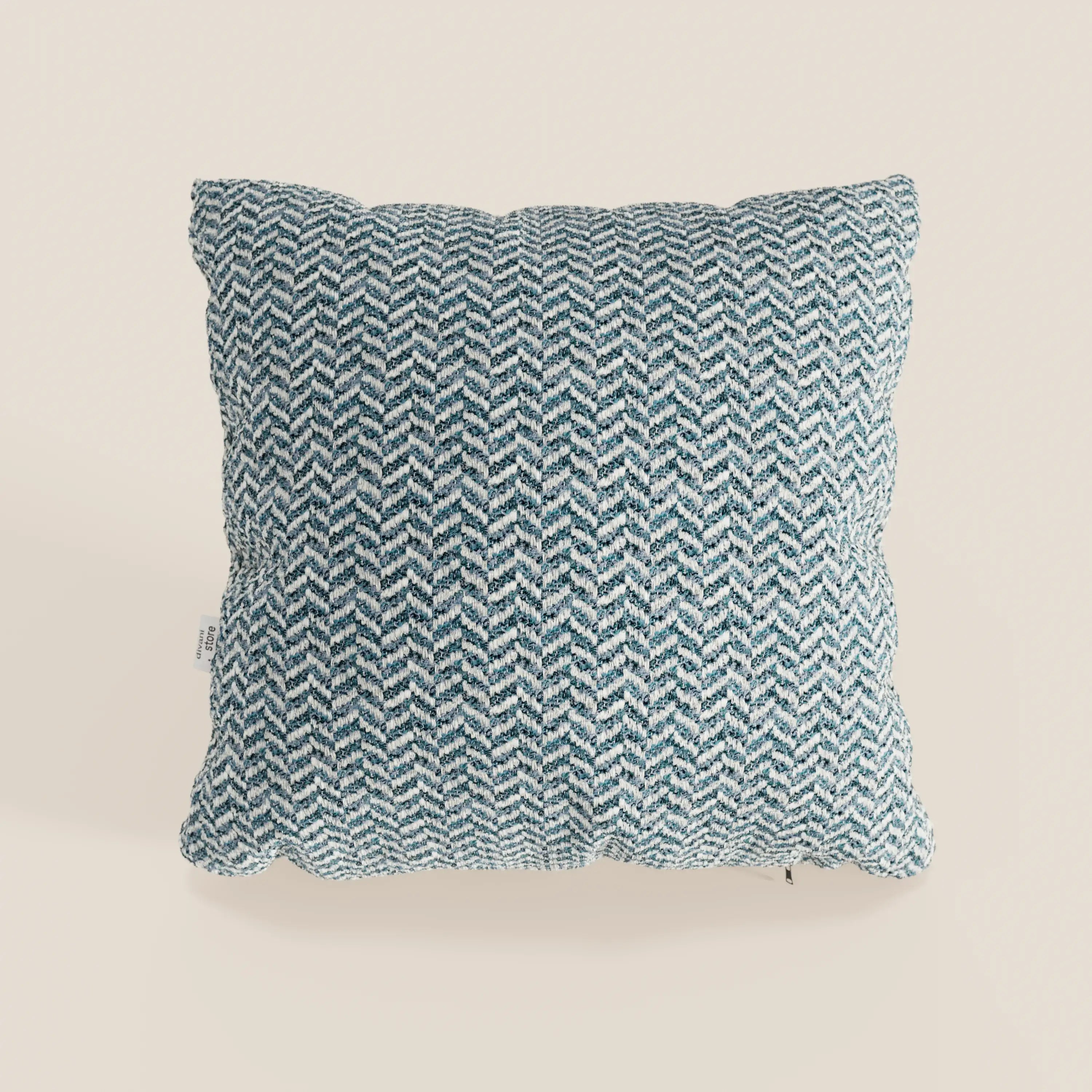 Il cuscino Sorrento 45x45 in lino di Divani.Store presenta una fodera con motivo a zig zag blu e bianco, è lavabile in lavatrice (cuscini lavabili in lavatrice), ha una piccola etichetta bianca sul lato sinistro ed è raffigurato su uno sfondo beige chiaro.