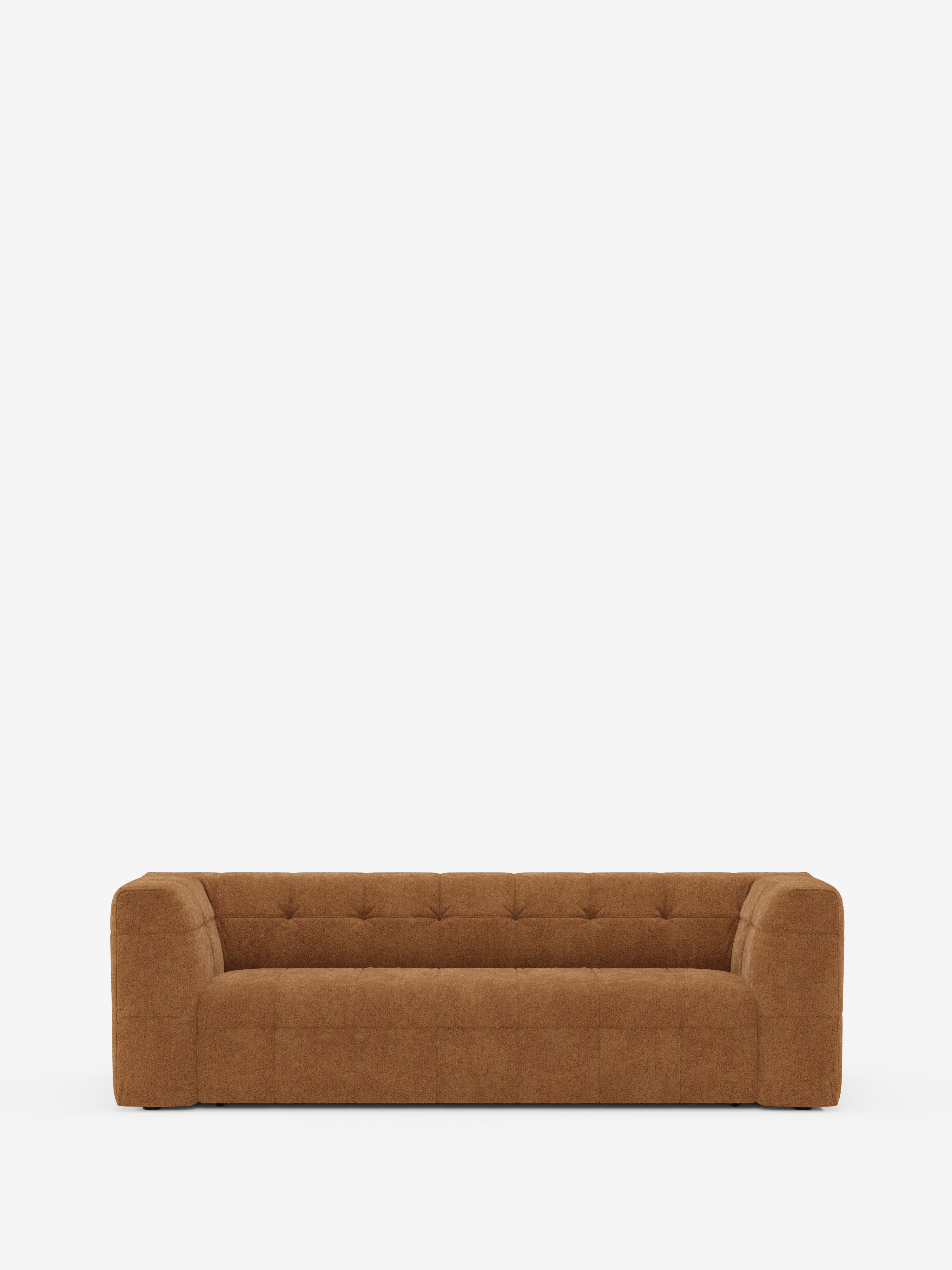Un divano componibile a 3 posti dal design contemporaneo e dal profilo basso, il “Mosaic Divano”, realizzato in bouclé da Divani.Store, caratterizzato da seduta e schienale capitonné, braccioli squadrati e una silhouette squadrata in tessuto T21 antimacchia, è posizionato al centro su uno sfondo bianco a tinta unita.