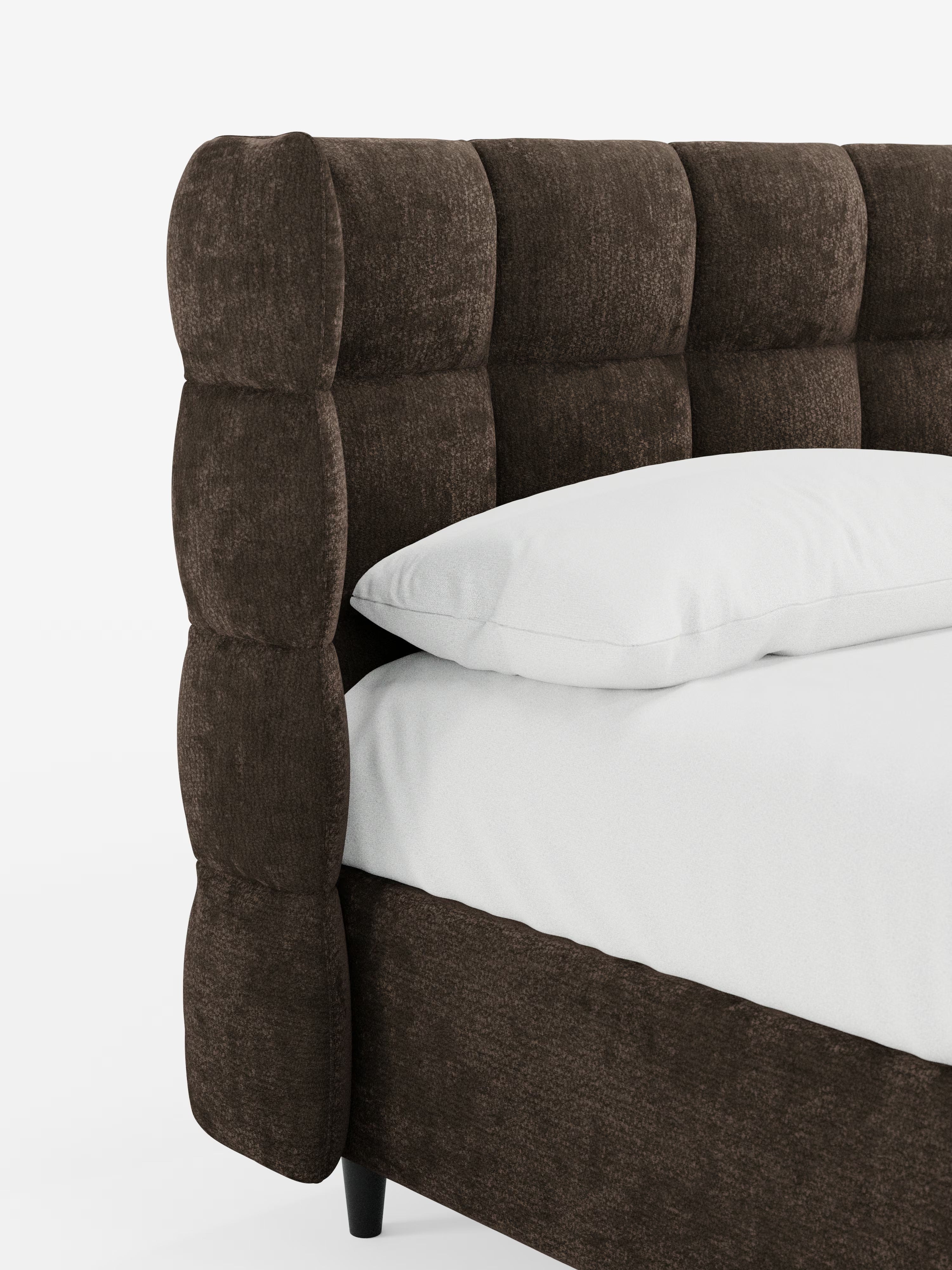 Primo piano del letto imbottito RAGNAR con contenitore e testiera capitonné avvolgente di Letti.store, realizzato con un elegante rivestimento marrone scuro certificato Oeko-Tex®. La testiera capitonné e la base presentano bordi arrotondati e imbottiti, poggianti su gambe corte e scure. Un cuscino bianco riposa su un materasso bianco abbinato, su uno sfondo bianco a tinta unita.