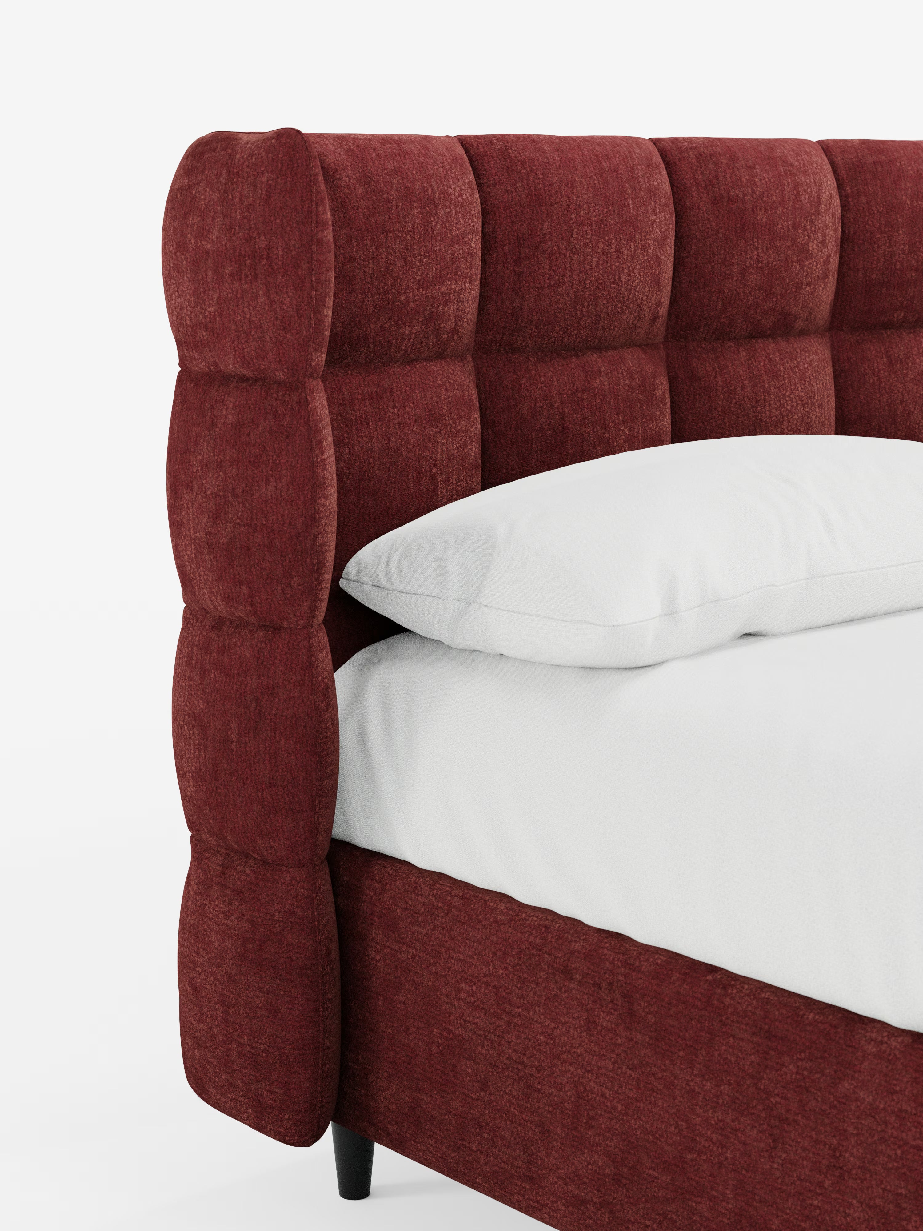 Primo piano del letto imbottito RAGNAR con contenitore e testiera capitonné avvolgente di Letti.store, rivestito con un elegante tessuto rosso intenso certificato Oeko-Tex®. La testiera presenta un raffinato motivo a griglia capitonné, che sottolinea lo stile sofisticato di questo letto contenitore. Sul letto, appoggiato su corte gambe nere, poggiano un cuscino e un materasso bianchi, che risaltano su uno sfondo bianco a tinta unita.