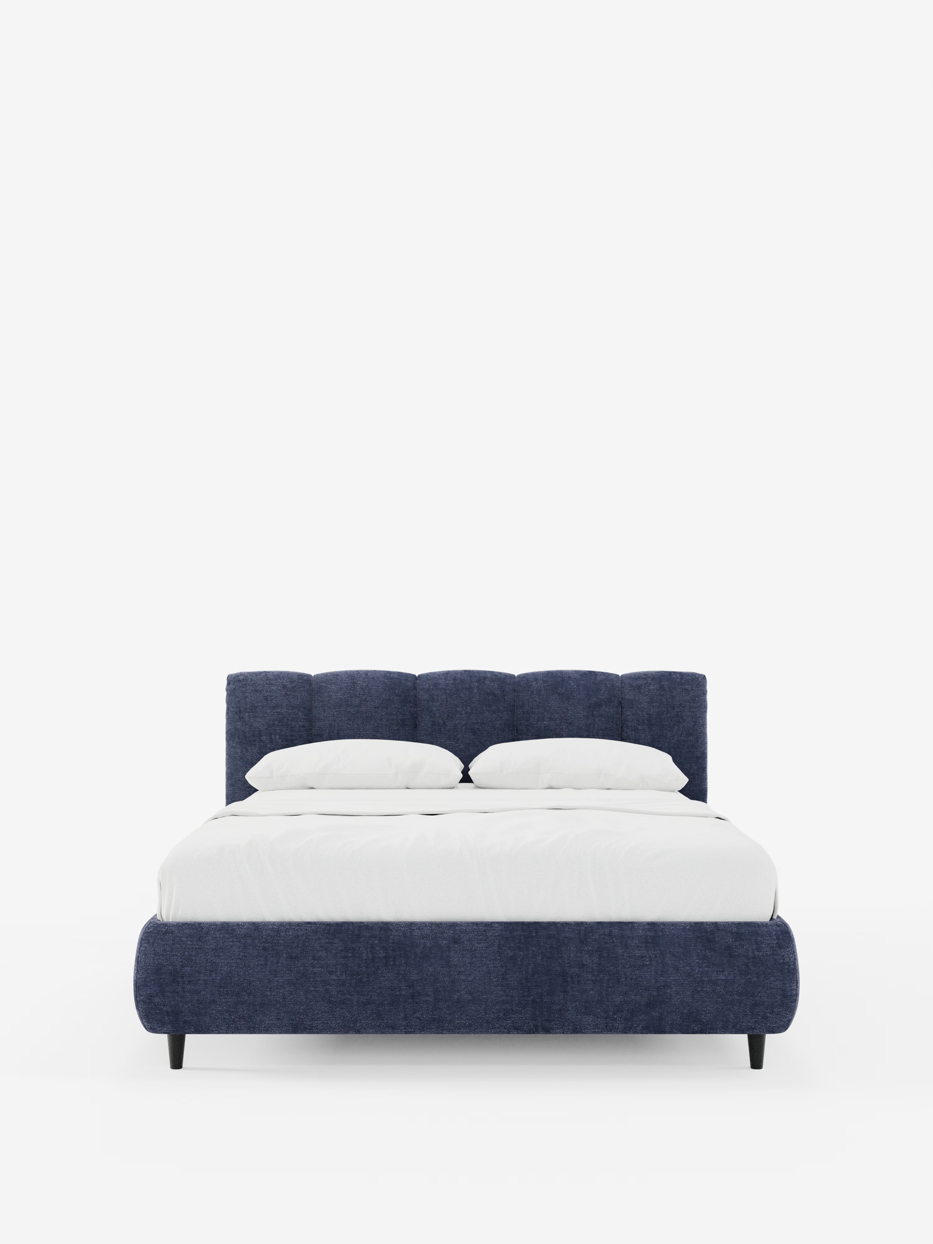 Il letto imbottito ARKAM con contenitore e testiera a cuciture verticali di Letti.store presenta una struttura imbottita di colore blu scuro, certificata Oeko-Tex®, e una testiera con cuciture verticali in un elegante stile shabby chic. Il letto è abbinato a un materasso bianco, due cuscini bianchi e un piumone bianco, il tutto su uno sfondo bianco a tinta unita.