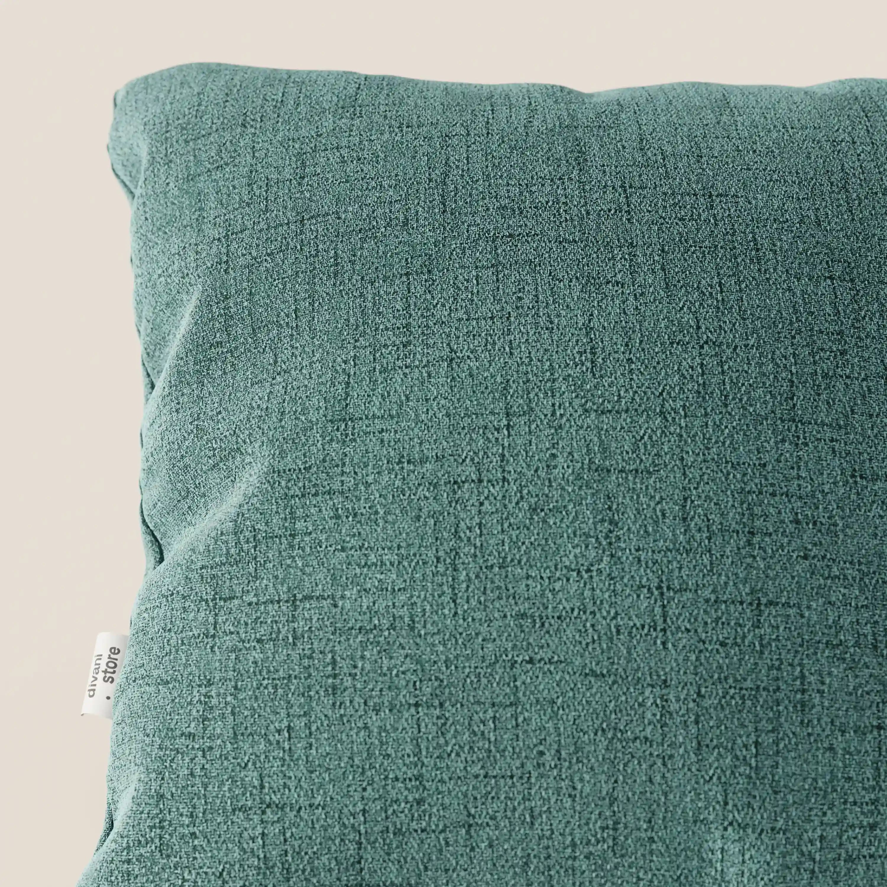 Primo piano del cuscino Felis 45x45 cm in T03 verde acqua di Divani.Store, realizzato in morbido tessuto idrorepellente con una sottile trama a griglia e una piccola etichetta laterale bianca, su uno sfondo beige chiaro.