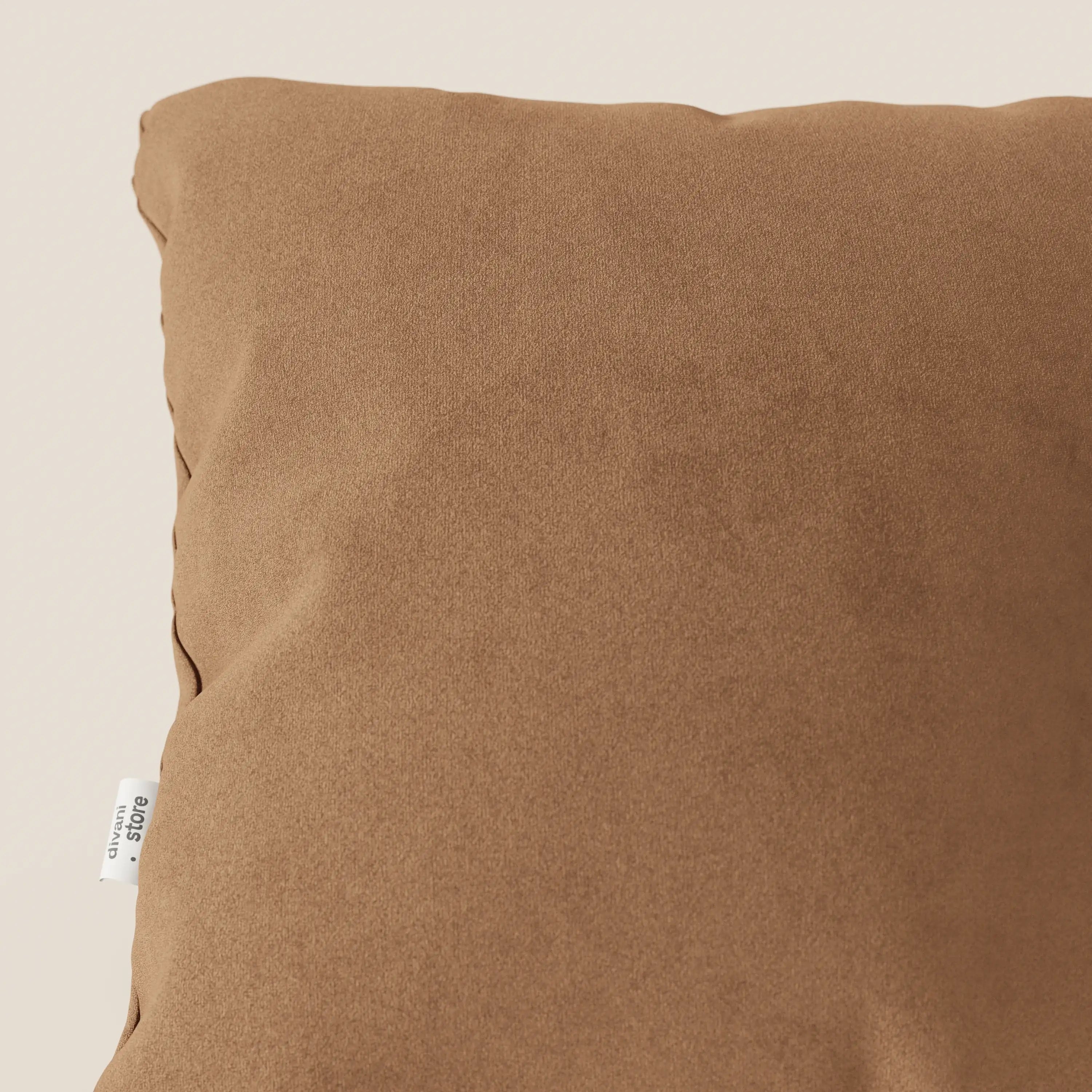 Primo piano del cuscino Jazz di Divani.Store, in T11 cuoio smacchiabile microfibra. Il cuscino quadrato presenta una consistenza morbida e un'etichetta in tessuto bianco sulla cucitura sinistra, su uno sfondo beige chiaro. Solo una parte è visibile.