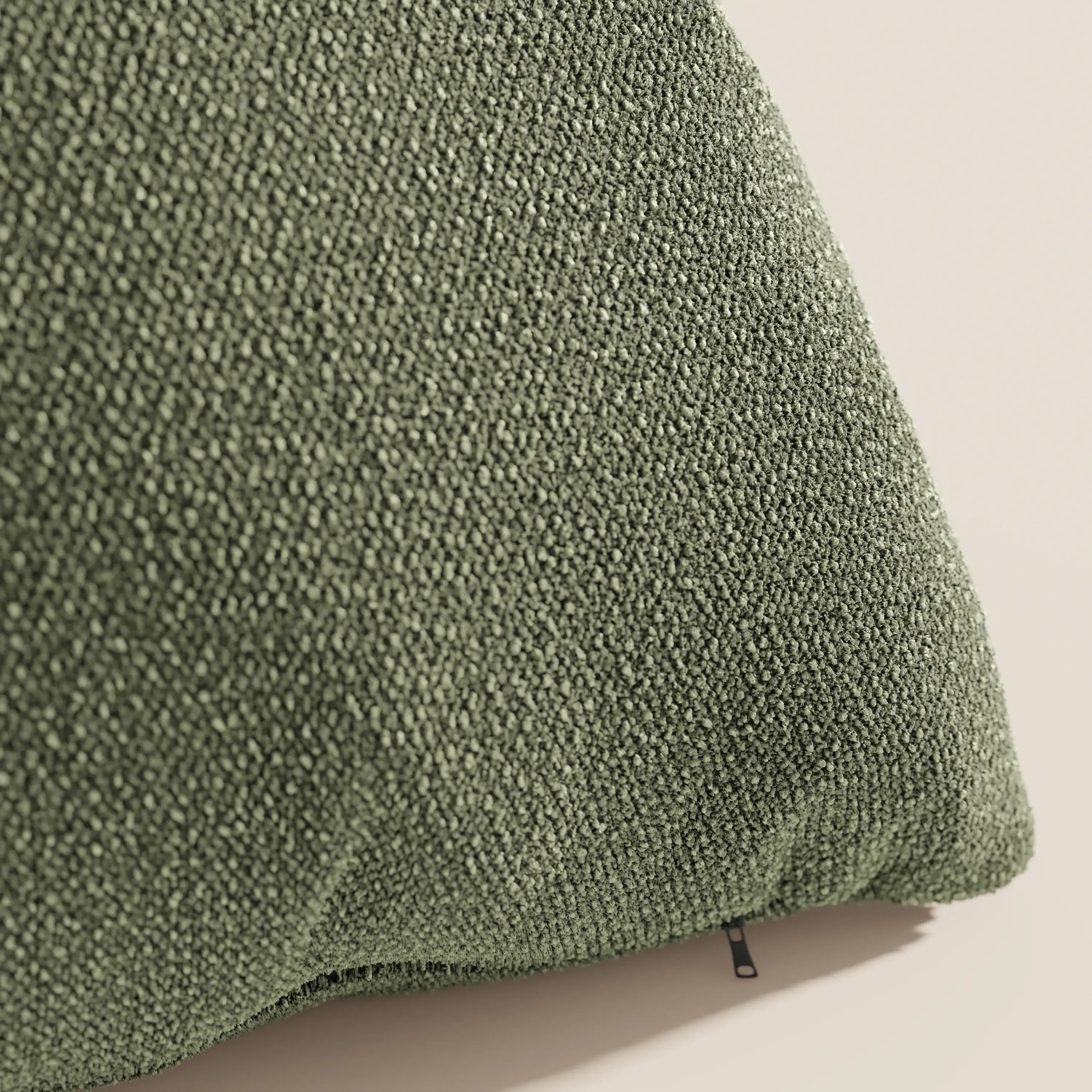 Primo piano del cuscino Lambada verde di Divani.Store, realizzato in tessuto T33 fresco, lavabile e impermeabile, dalla consistenza simile al cotone. La cerniera visibile è nell'angolo inferiore su uno sfondo chiaro e neutro.