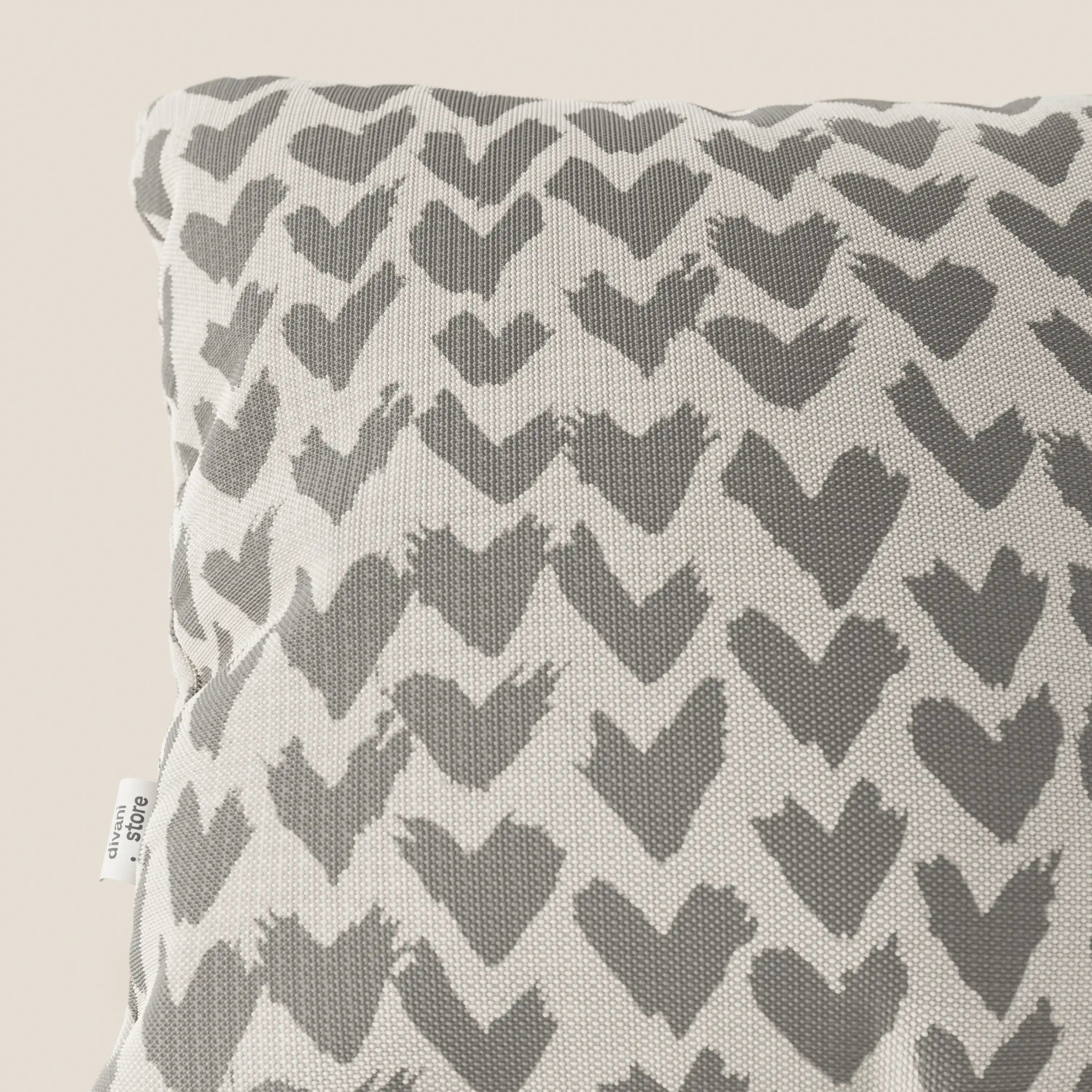 Primo piano dei cuscini geometrici Arrow di Divani.Store, disponibili in vari colori, realizzati in tessuto idrorepellente grigio. Sul bordo sinistro del cuscino compare una piccola etichetta in tessuto bianco con testo.