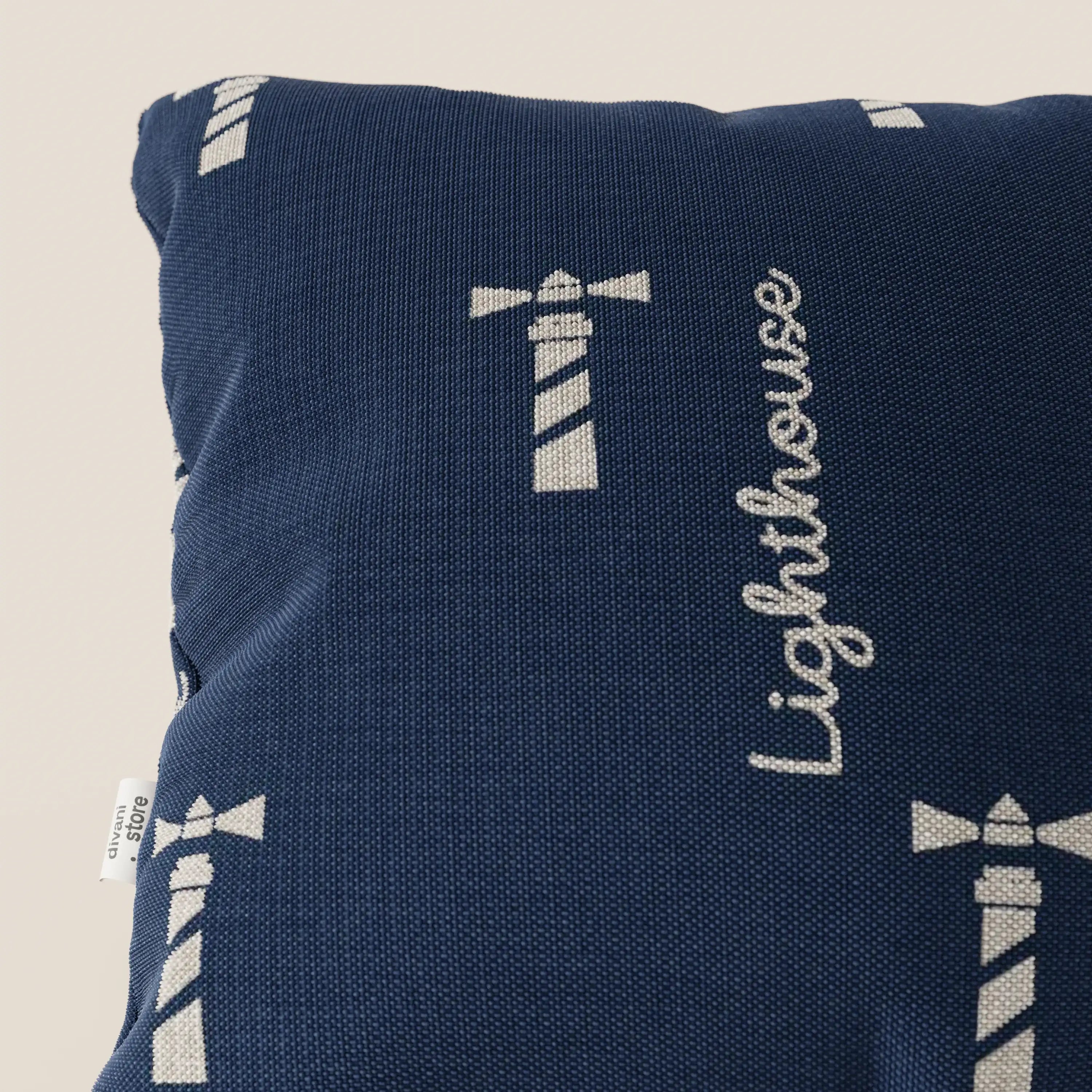 Il cuscino della collezione Nautilus di Divani.Store è caratterizzato da un tessuto impermeabile blu navy con disegni di fari bianchi e scritta "Lighthouse", oltre a una targhetta laterale per aggiungere fascino: l'ideale per portare lo stile nautico nel vostro spazio.