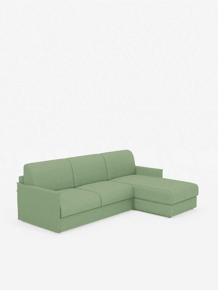 Un divano letto angolare Evans di colore verde chiaro con penisola contenitore di Divani.Store, caratterizzato da un design compatto in tessuto T23 antimacchia, tre cuscini di seduta, braccioli bassi e squadrati e una chaise longue sul lato destro, il tutto su uno sfondo bianco a tinta unita.