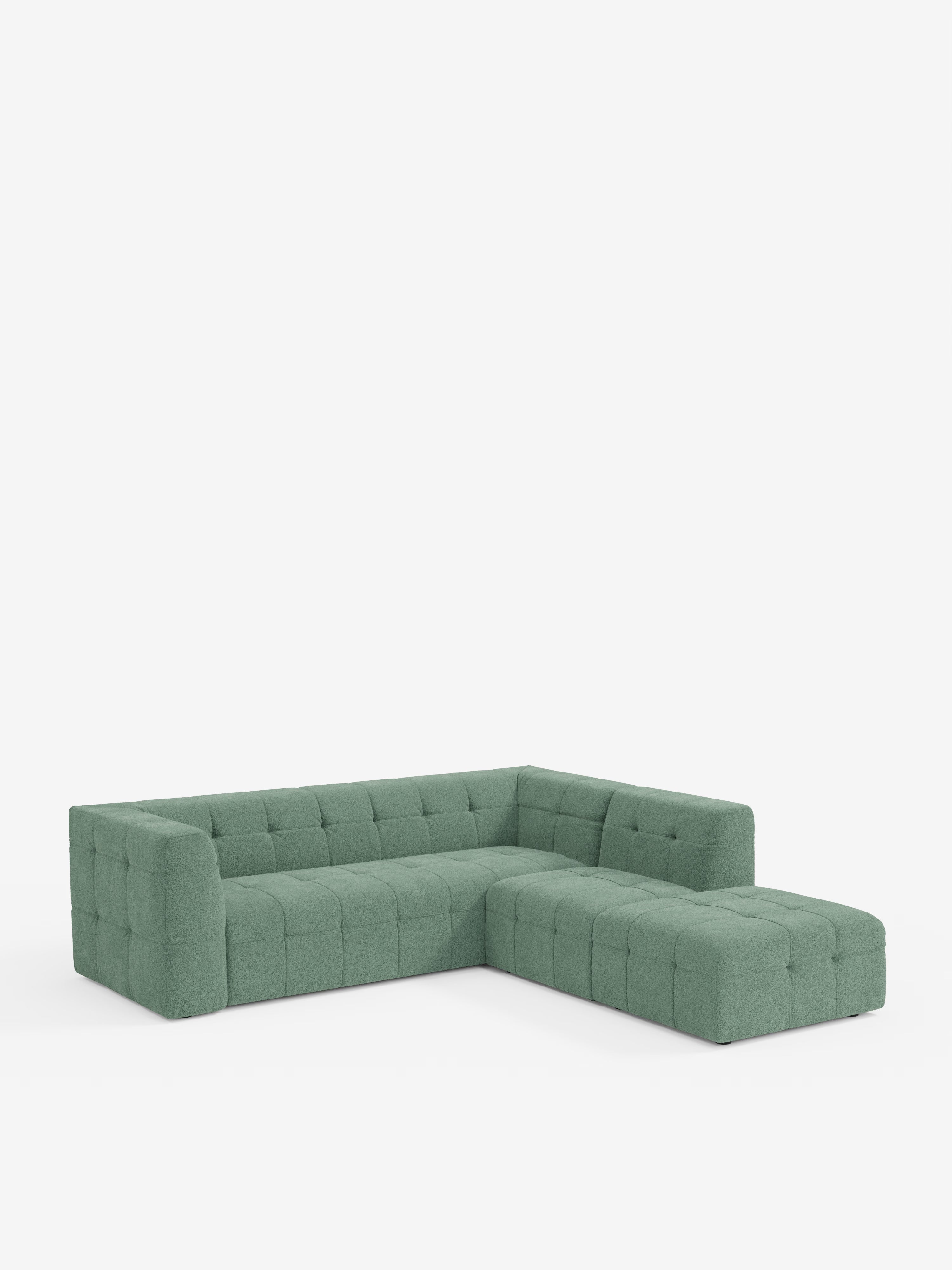 Un moderno divano componibile a L: il divano angolare componibile e modulare Mosaic in bouclé di Divani.Store è rivestito in tessuto T21 verde antimacchia, con cuscini capitonné su seduta, schienale e fianchi. Il divano poggia direttamente sul pavimento senza gambe visibili ed è raffigurato su uno sfondo bianco a tinta unita.