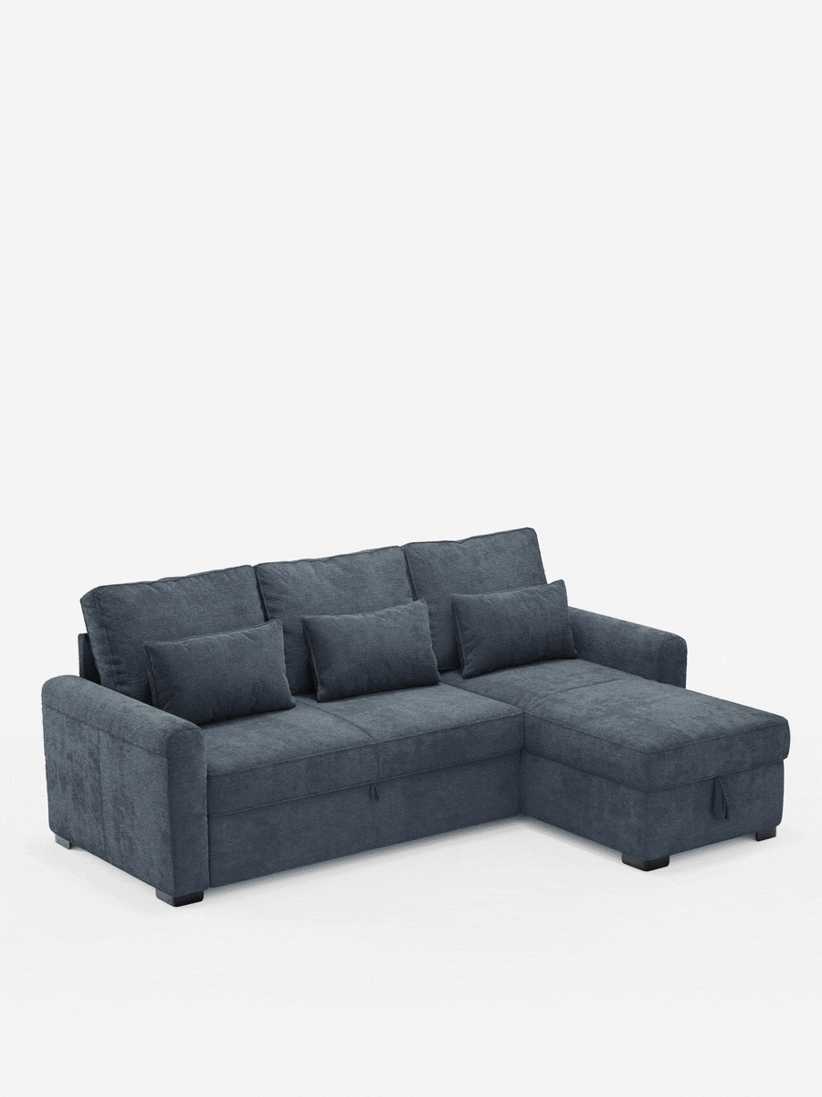 Un divano letto Ottaviano con letto estraibile, penisola reversibile e contenitore in tessuto materico smacchiabile, caratterizzato da una sezione in grigio scuro con chaise longue, tre cuscini dello schienale e tre cuscini lombari su uno sfondo a tinta unita.