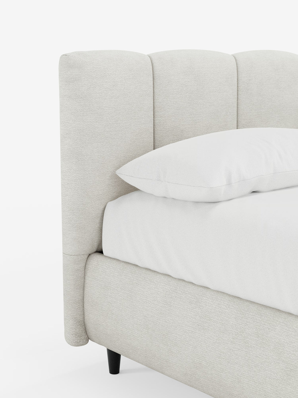 Un primo piano del letto imbottito con contenitore ARKAM di Letti.store mette in risalto il suo design moderno in stile shabby chic, con una testiera imbottita in tessuto certificato Oeko-Tex® di colore beige chiaro e con cuciture verticali. Il letto presenta una struttura imbottita in tinta, gambe affusolate in legno nero ed è abbinato a biancheria da letto bianca e un unico cuscino bianco su uno sfondo bianco a tinta unita.