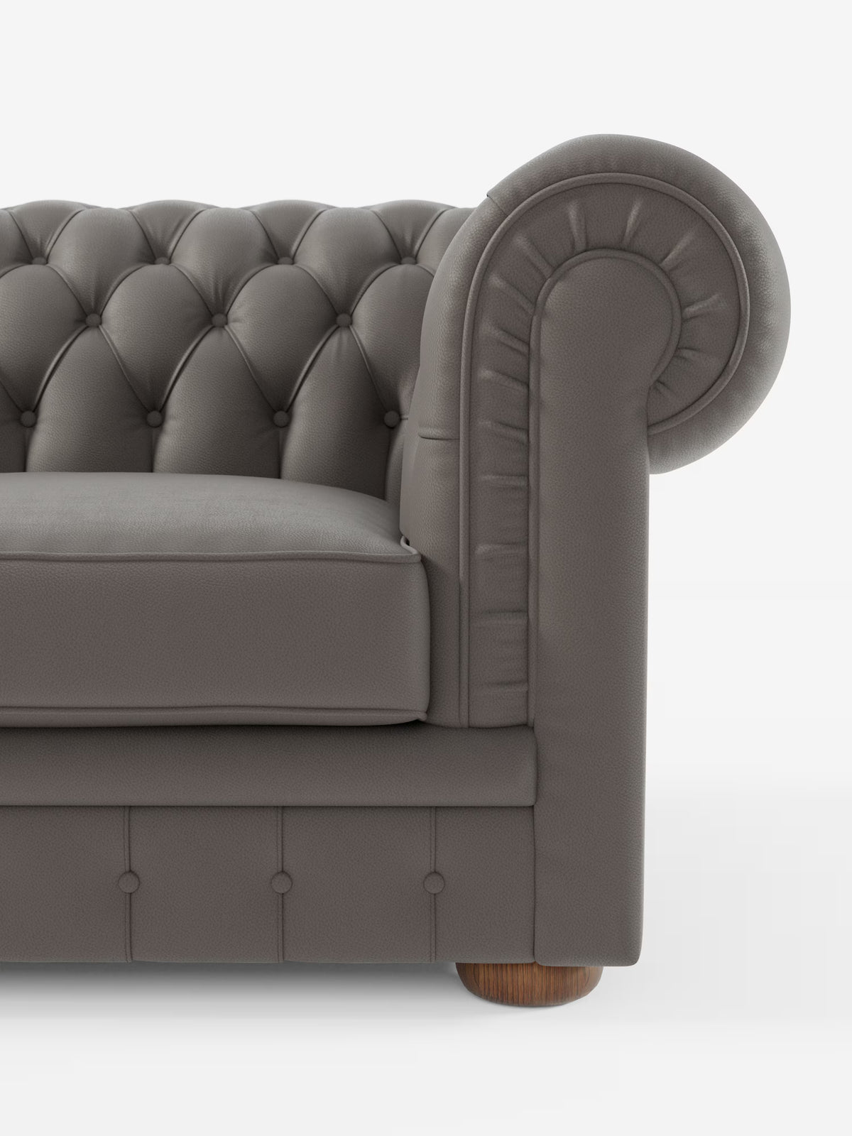 Un primo piano del Chester – Divano Chesterfield in vera pelle spessorata a 2 e 3 posti di Divani.Store mostra la metà sinistra di questo elegante divano italiano realizzato a mano. L’immagine mostra un bracciolo grigio trapuntato dal design arrotondato, una seduta imbottita, dettagli con bottoni e una gamba cilindrica in legno su sfondo bianco.