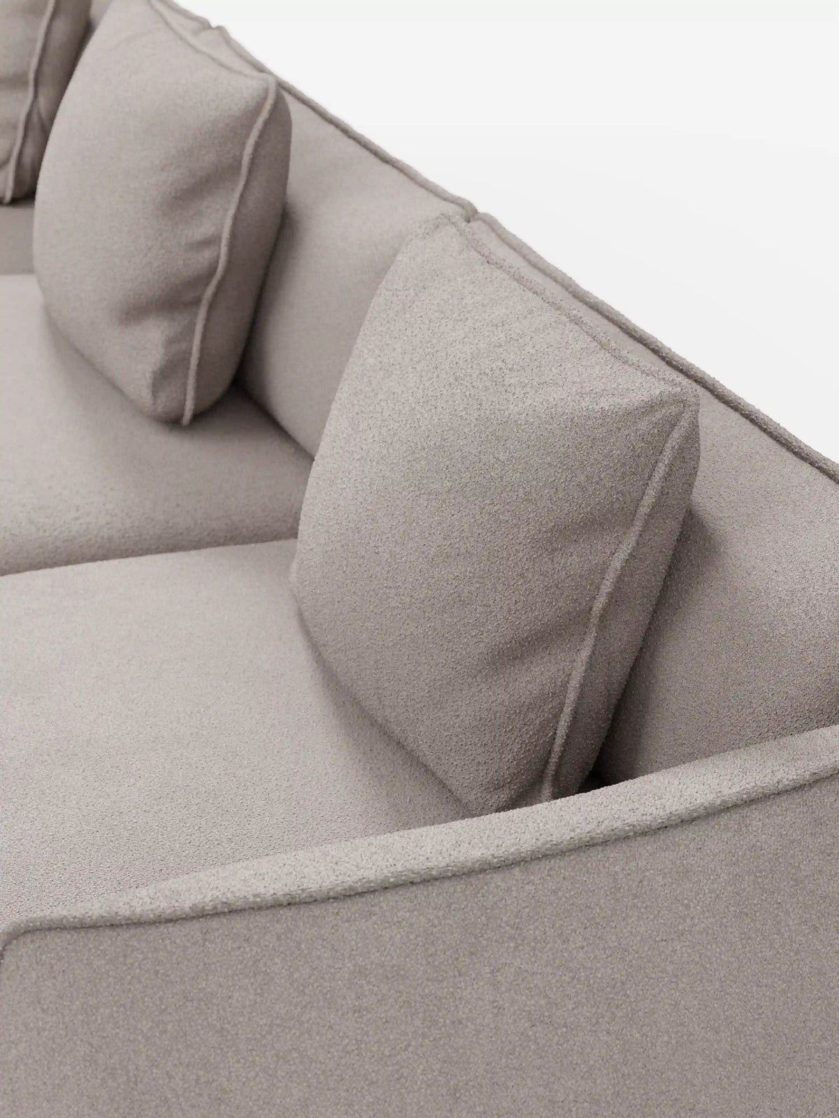 Primo piano del divano modulare a 3 posti Nimbus, realizzabile in morbido tessuto smacchiabile effetto cotone T33 di Divani.Store. Questo elegante divano color beige chiaro presenta due cuscini dello schienale quadrati e un bracciolo, con un tessuto morbido e dalla trama delicata che ne esalta il fascino moderno. Su uno sfondo bianco a tinta unita, le sue linee pulite e il design minimalista lo rendono un complemento d’arredo versatile per qualsiasi ambiente.