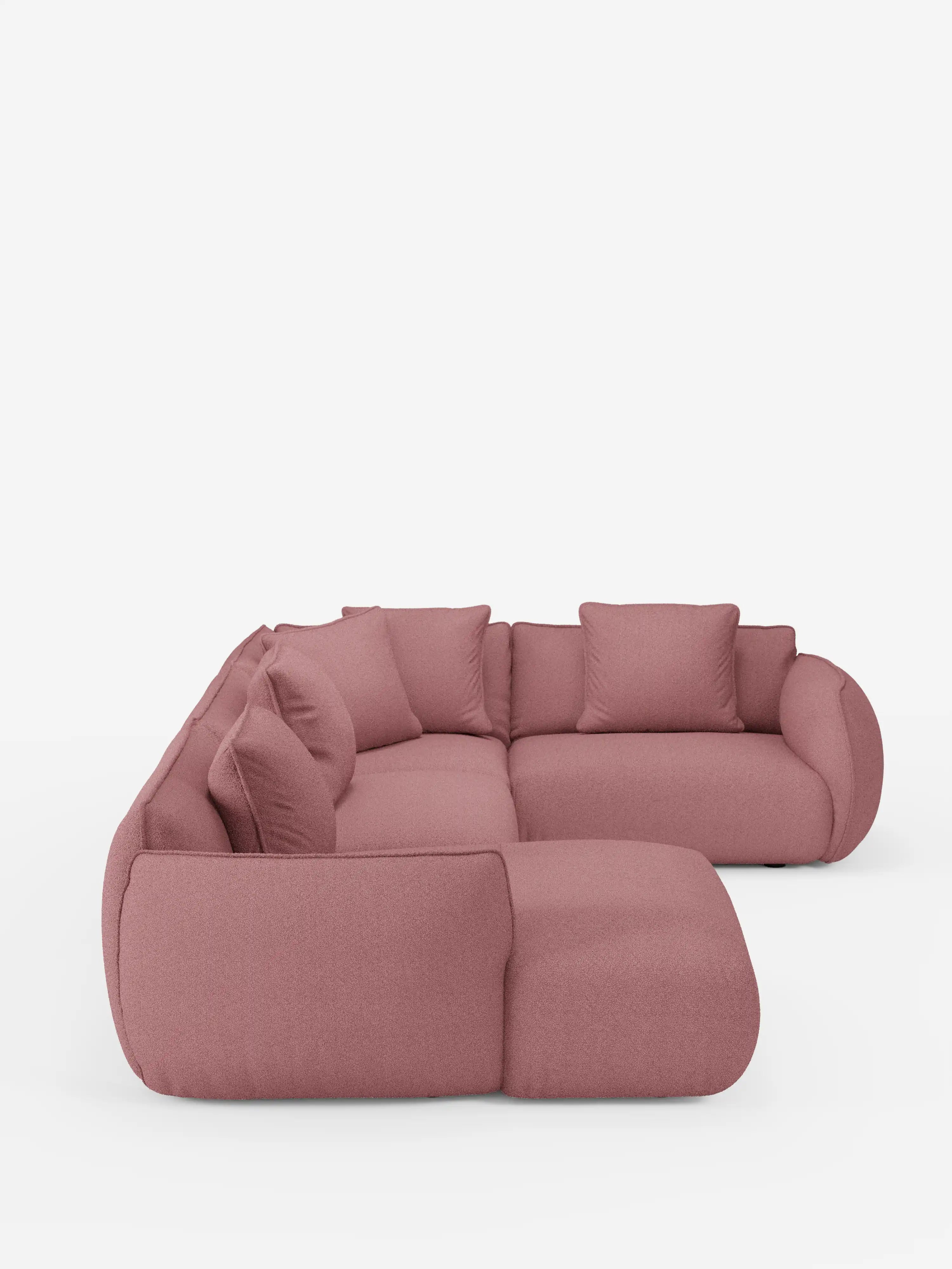 Un moderno divano angolare panoramico componibile Nimbus con penisola e angolo in tessuto smacchiabile T33 di Divani.Store, rivestito in tessuto rosa tenue e caratterizzato da cinque grandi cuscini dello schienale e ampi braccioli arrotondati, su uno sfondo bianco a tinta unita.