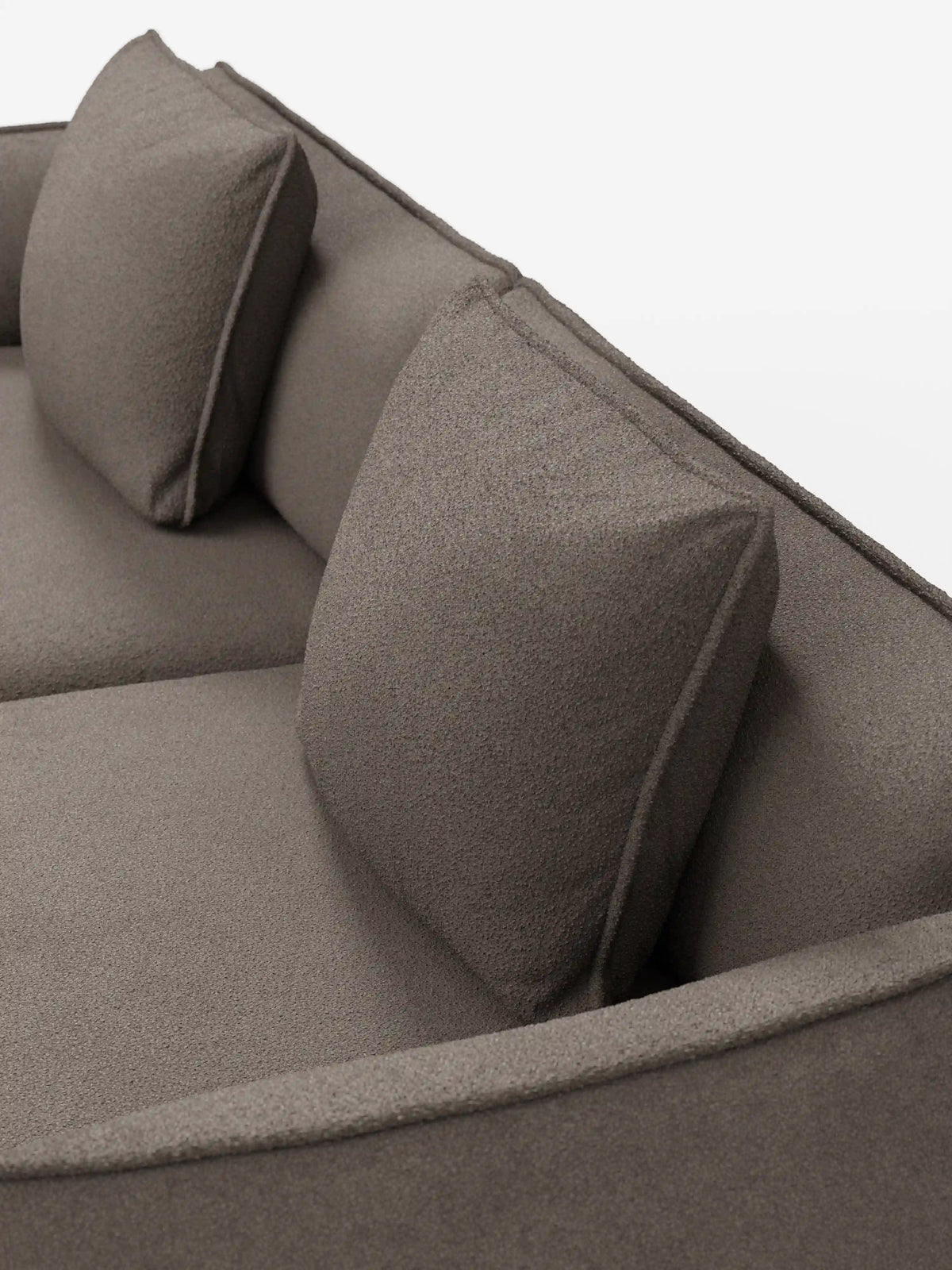 Un primo piano del divano Nimbus a 3 posti, modulare e componibile da 250 cm di Divani.Store, rivestito in tessuto T33 effetto cotone, testurizzato e resistente alle macchie, con due cuscini quadrati coordinati per lo schienale. Il divano presenta un design moderno e minimalista dalle linee pulite ed è ripreso su uno sfondo bianco a tinta unita.
