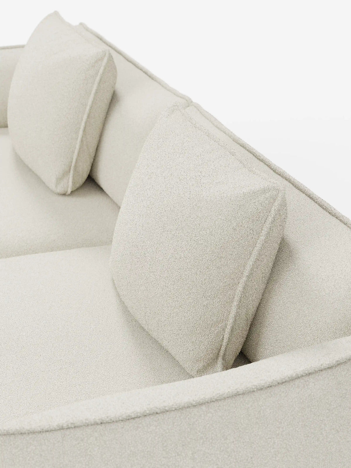 Primo piano del divano modulare e componibile Nimbus a 3 posti di Divani.Store, rivestito in tessuto beige effetto cotone antimacchia (tessuto smacchiabile effetto cotone t33). Due cuscini quadrati coordinati poggiano contro lo schienale basso del divano. La morbida trama è chiaramente visibile sotto una luce intensa, accentuando le linee moderne e minimaliste e la versatile modularità di questo divano contemporaneo da 250 cm.