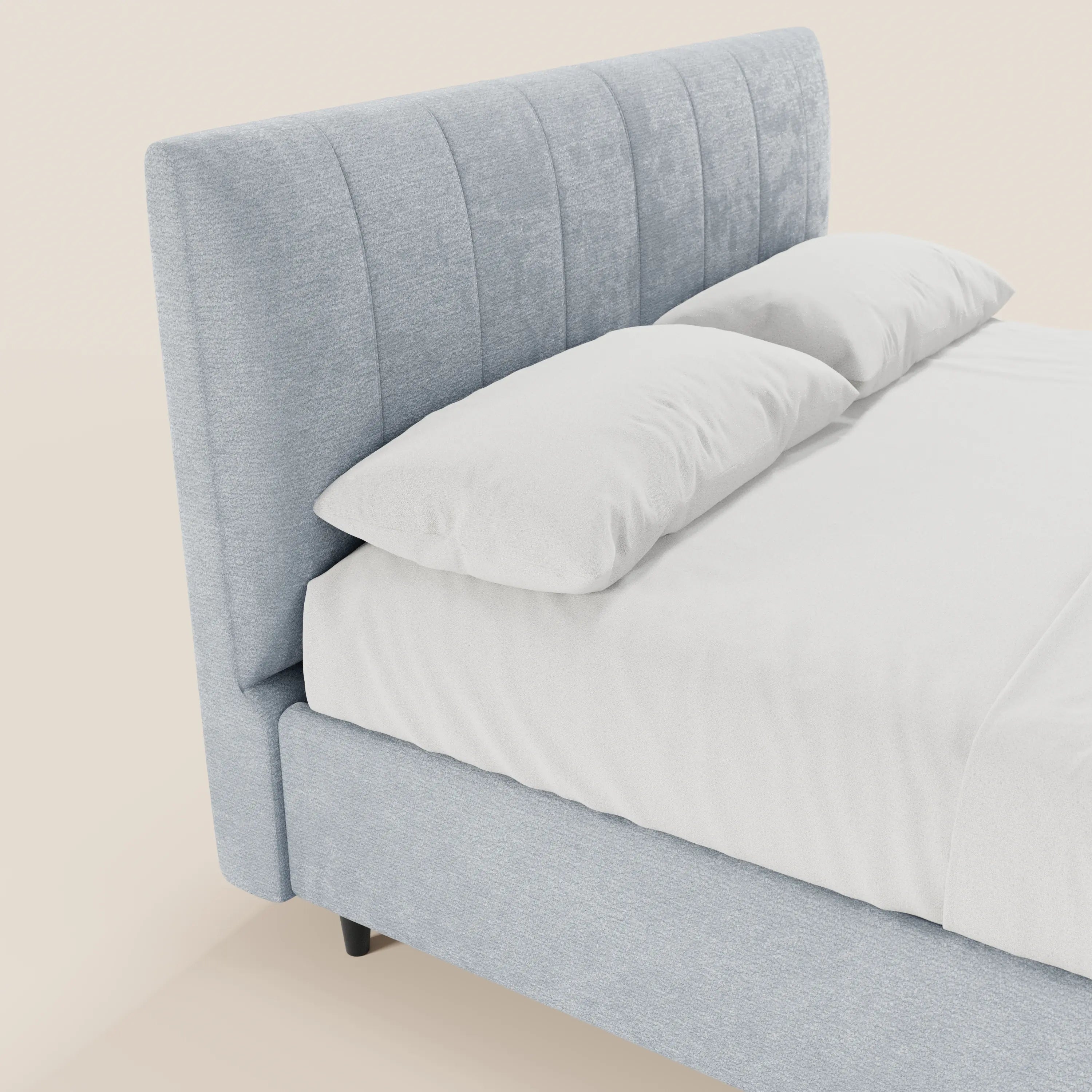 Un primo piano del letto imbottito con contenitore ONYX di Letti.store, caratterizzato da una testiera alta in tessuto azzurro certificato Oeko-Tex® con cuciture verticali, rifinito con cura con lenzuola e cuscini bianchi su uno sfondo chiaro.