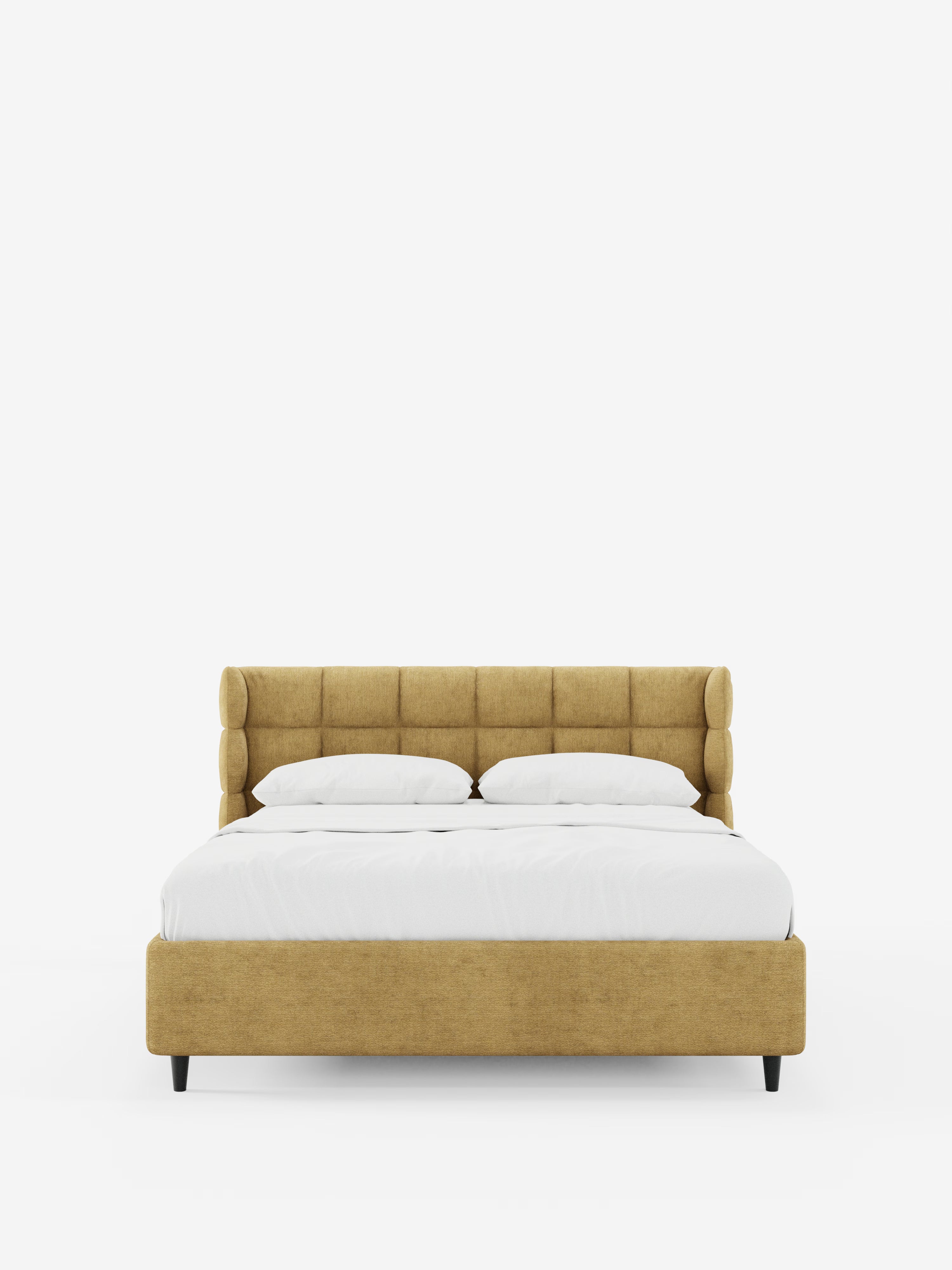 Un moderno letto imbottito RAGNAR con contenitore e testiera capitonné avvolgente di Letti.store, rivestito in un elegante tessuto giallo senape certificato Oeko-Tex®, è ripreso di fronte su uno sfondo bianco a tinta unita. Il letto è caratterizzato da due cuscini, biancheria da letto bianca, gambe corte nere e un design minimalista.