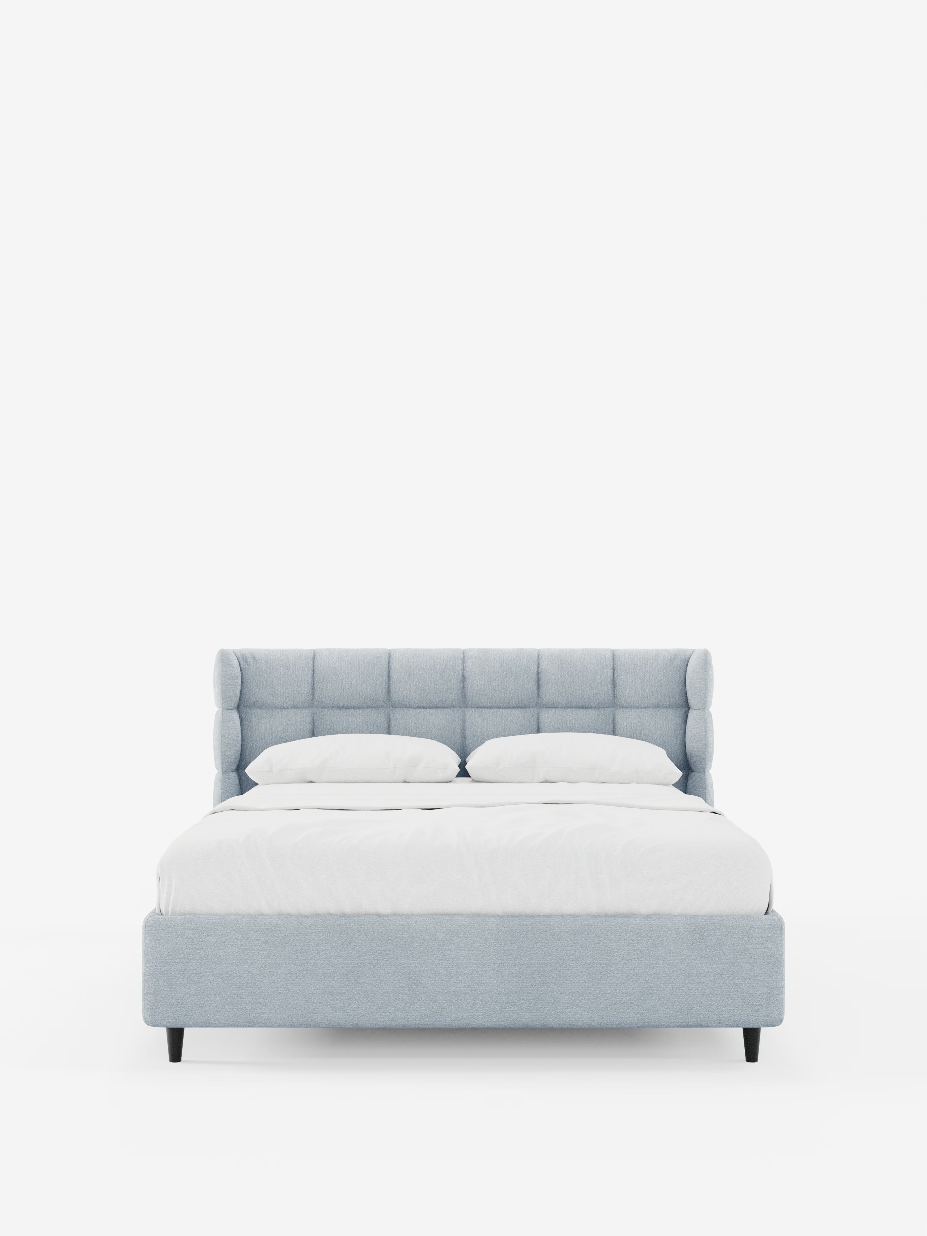 Una vista frontale del letto imbottito RAGNAR con contenitore e testiera capitonné avvolgente di Letti.store, rivestito in un elegante tessuto azzurro certificato Oeko-Tex®, caratterizzato da una testiera capitonné avvolgente, biancheria da letto bianca e due cuscini su uno sfondo bianco a tinta unita.