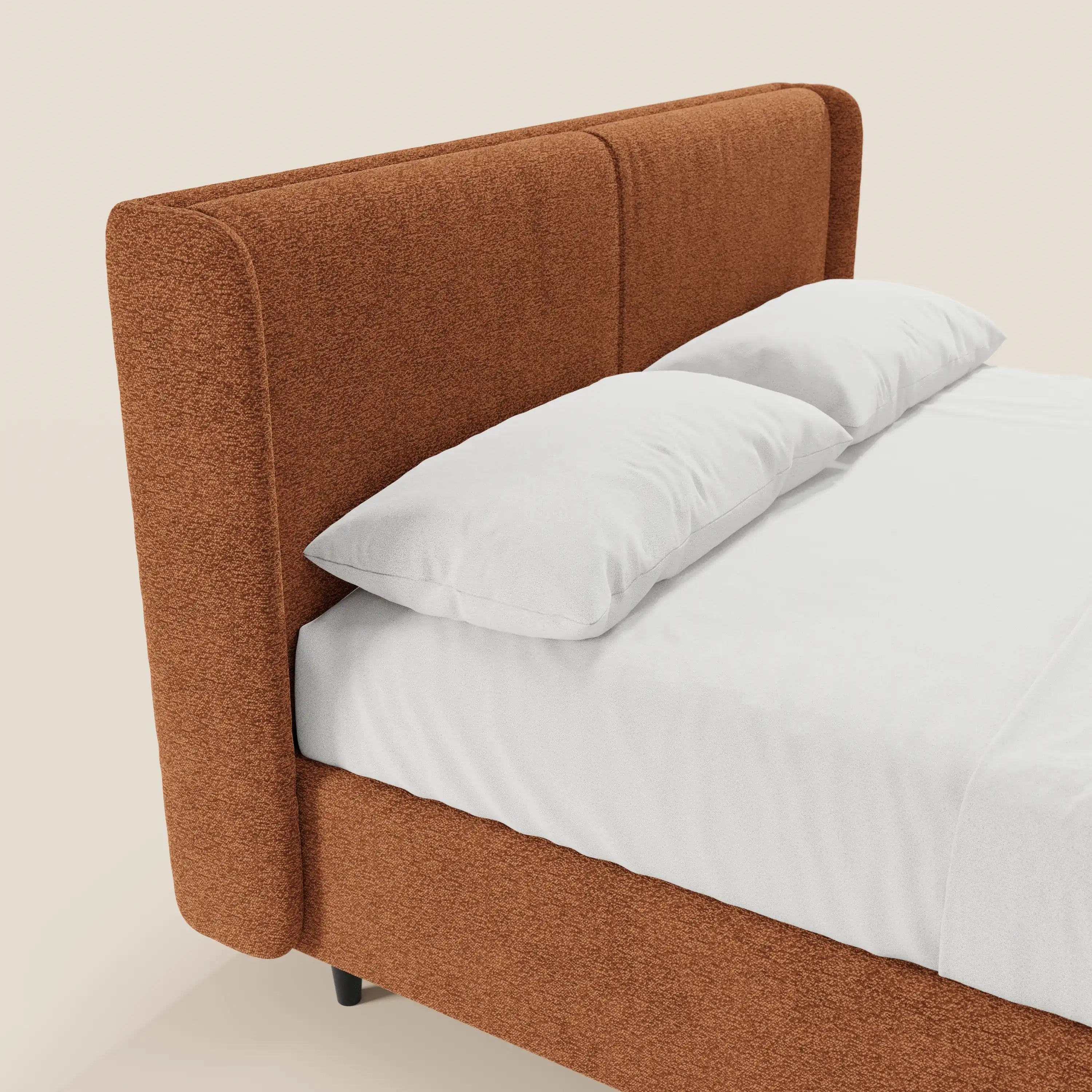Il letto di design VALKIRIA di Letti.store presenta una testiera avvolgente e una base rivestite in tessuto color ruggine certificato Oeko-Tex®, con 2 cuscini imbottiti, un vano contenitore, un lenzuolo bianco su misura e cuscini, per un tocco di eleganza moderna su uno sfondo neutro e chiaro.