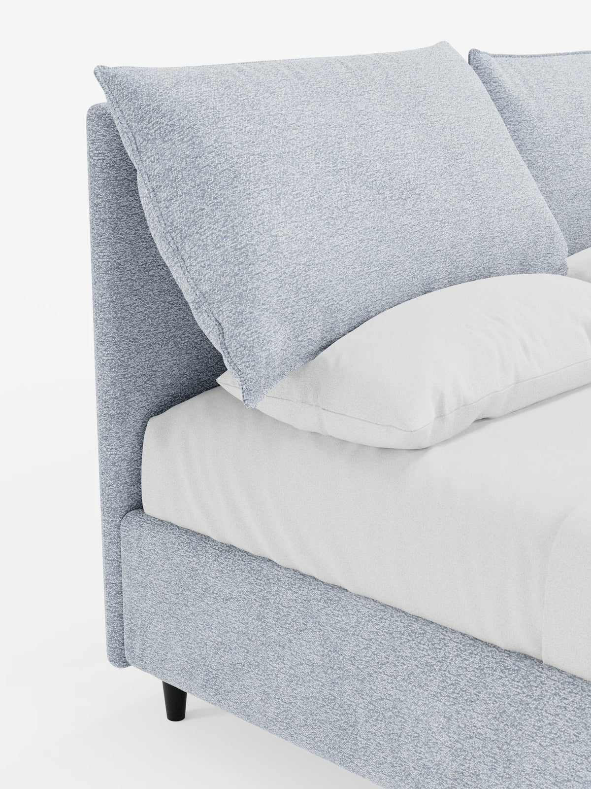 Una vista laterale ravvicinata del letto imbottito ZAYRON con contenitore e morbidi cuscini regolabili di Letti.store, un moderno letto imbottito in tessuto azzurro certificato Oeko-Tex®, caratterizzato da grandi cuscini imbottiti regolabili sulla testiera e da un lenzuolo bianco sporco, presentato su uno sfondo bianco.