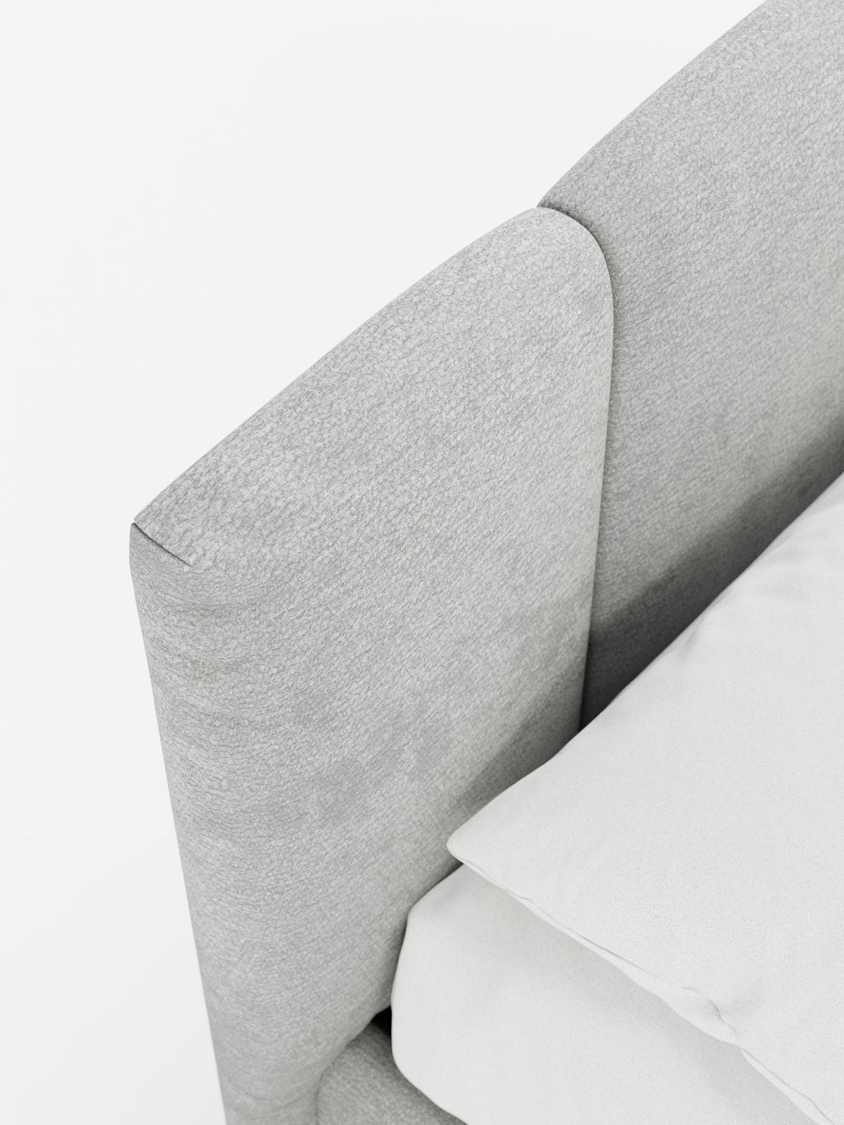 Primo piano del letto imbottito ARKAM di Letti.store, caratterizzato da una testiera grigio chiaro con cuciture verticali in tessuto certificato Oeko-Tex® e dal raffinato design curvo. La testiera fa da cornice a un cuscino bianco e a un lenzuolo disposti con cura, mettendo in risalto la morbida consistenza e lo stile shabby chic pulito e minimalista sullo sfondo bianco.