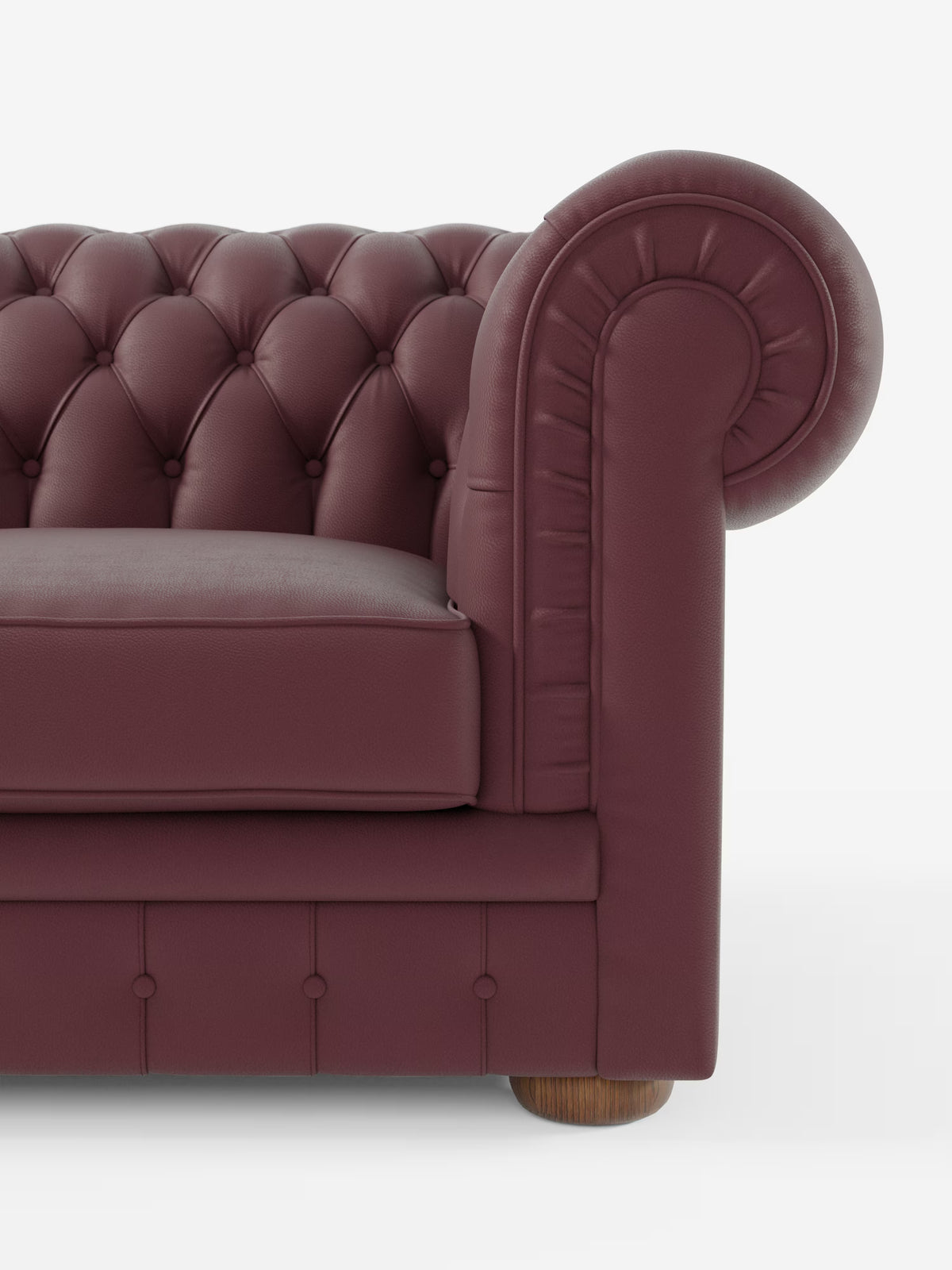 Un primo piano del Chester – Divano Chesterfield in vera pelle spessorata a 2 e 3 posti di Divani.Store mette in risalto la profonda trapuntatura a bottoni, i braccioli generosamente arrotondati e le gambe in legno che risaltano sullo sfondo bianco. Il morbido cuscino di seduta e il rivestimento in pelle liscia color bordeaux sottolineano i classici dettagli di design artigianale caratteristici di un divano artigianale Made in Italy.