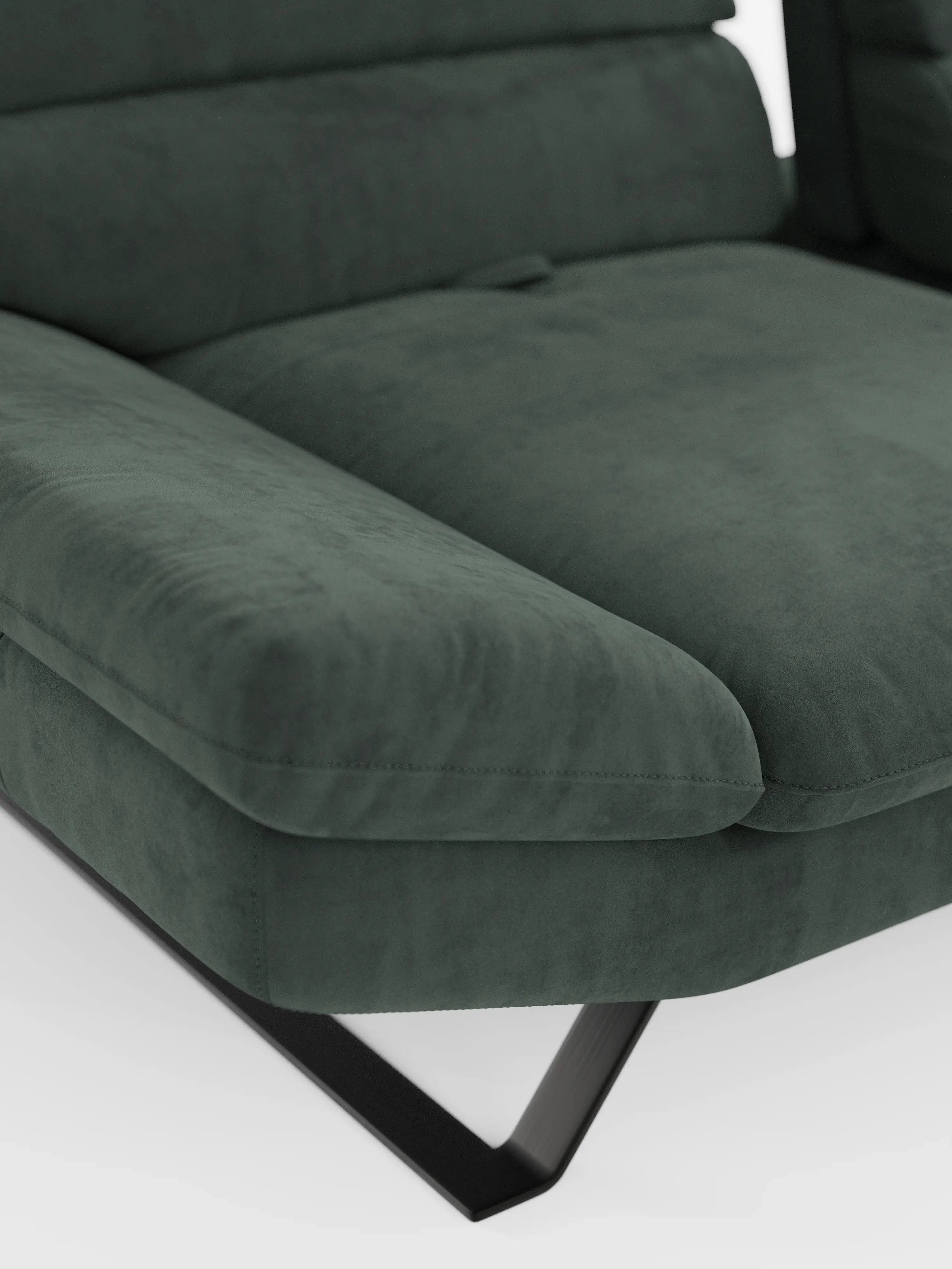Primo piano del divano angolare con penisola e schienali traslanti “Eclipse” di Divani.Store, rivestito in microfibra tecnica T11 verde scuro, resistente alle macchie e dalla consistenza liscia e vellutata. Il morbido tessuto riveste i braccioli imbottiti e i generosi cuscini della seduta, mentre le gambe angolari in metallo nero completano il look su uno sfondo bianco a tinta unita.