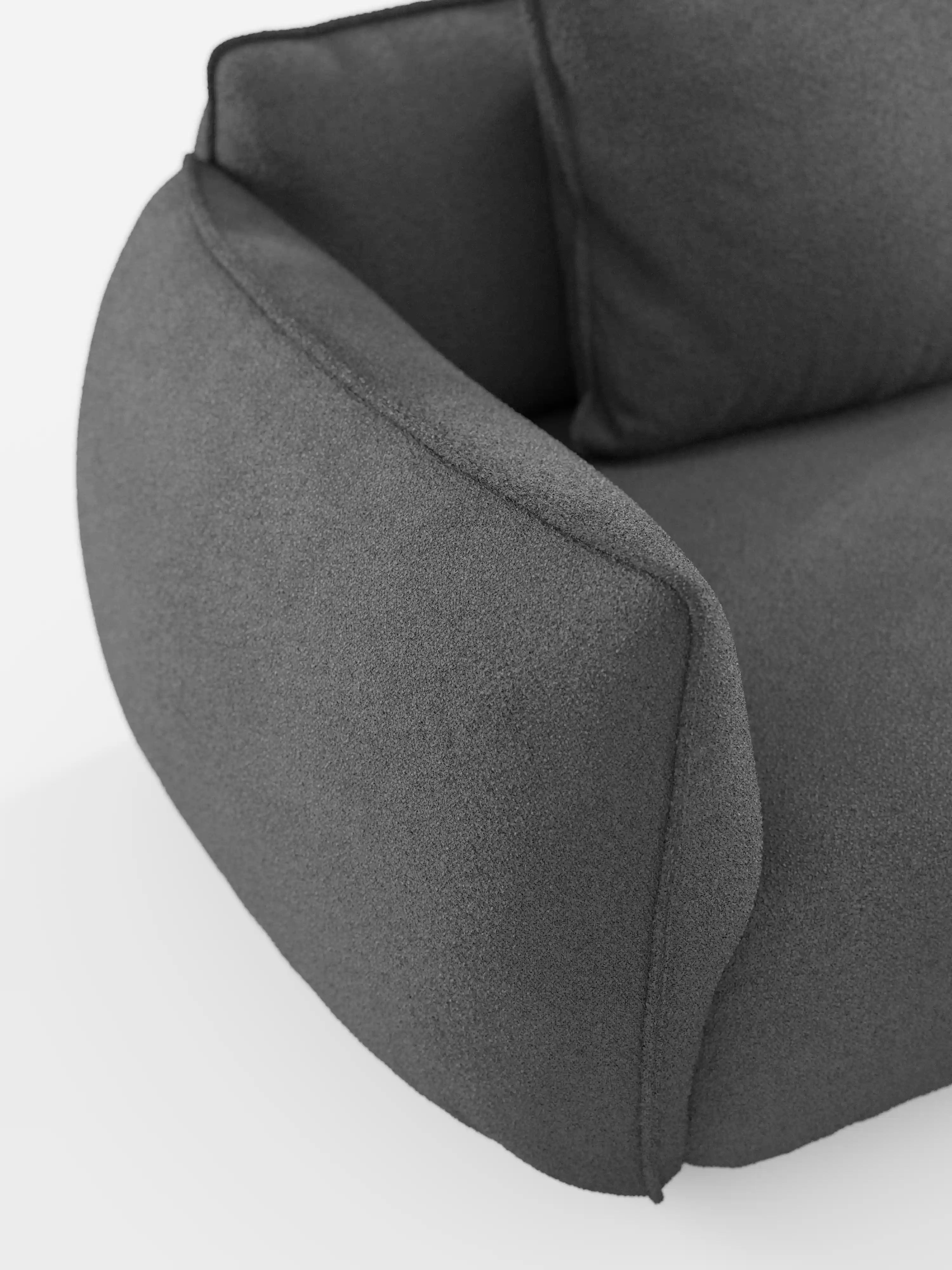 Un primo piano del bracciolo e dello schienale del divano angolare con penisola componibile Nimbus di Divani.Store, rivestito in morbido tessuto T33 effetto cotone, resistente alle macchie e dalla trama rigata, in grigio scuro. Lo sfondo bianco ne accentua le forme delicatamente arrotondate ed esalta l’eleganza moderna e minimalista di questo elemento d’arredo contemporaneo.