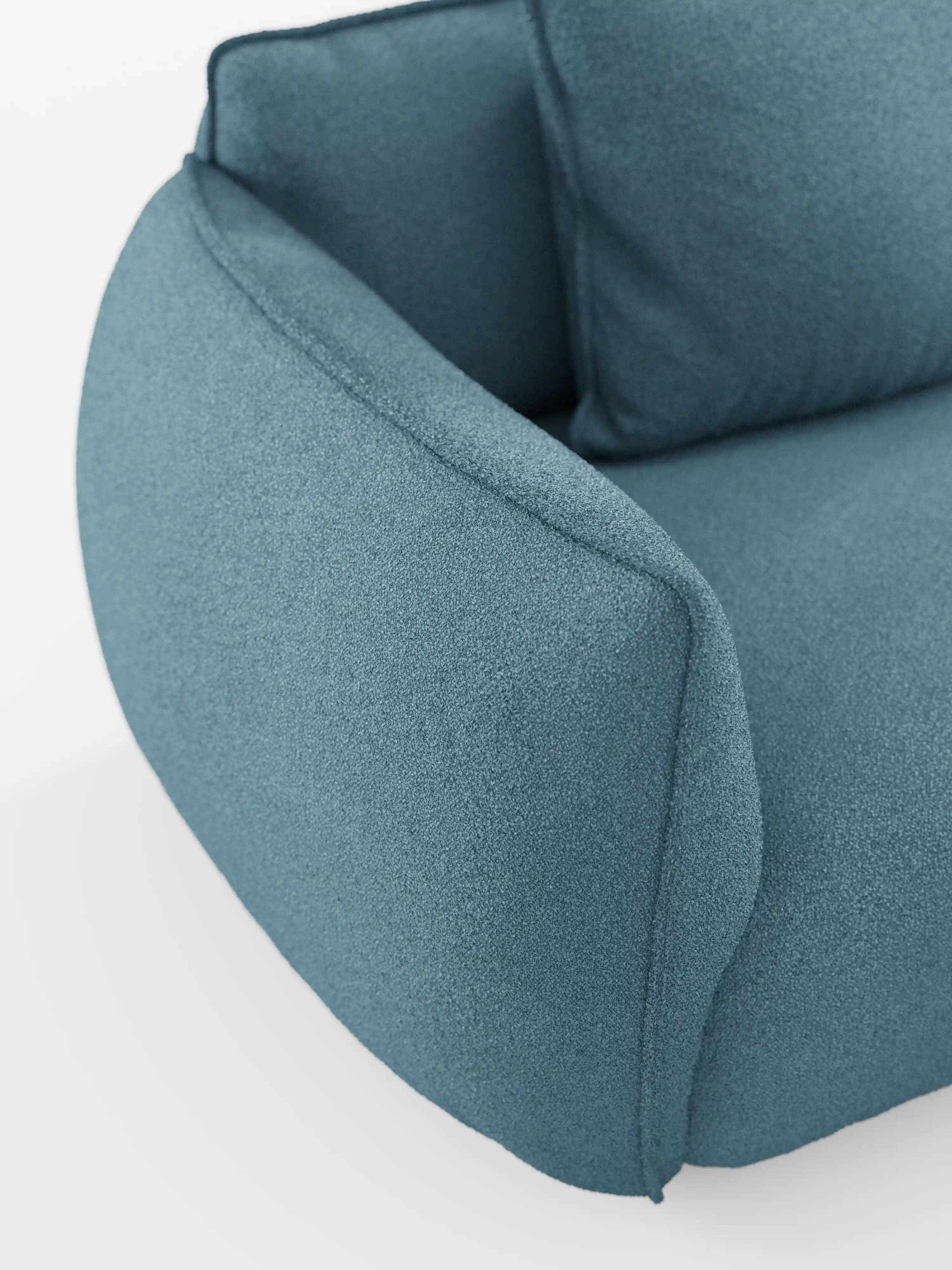 Primo piano del divano angolare con penisola componibile Nimbus di Divani.Store, che mette in risalto i braccioli e lo schienale rivestiti in morbido tessuto T33 effetto cotone, resistente alle macchie. Il tessuto color verde acqua con texture e le linee arrotondate e morbide, con bordi delicati, sono caratterizzati da cuciture a vista: un tratto distintivo del design di alta gamma dei divani. Su uno sfondo bianco a tinta unita, il colore e la silhouette sinuosa del divano sono protagonisti assoluti.