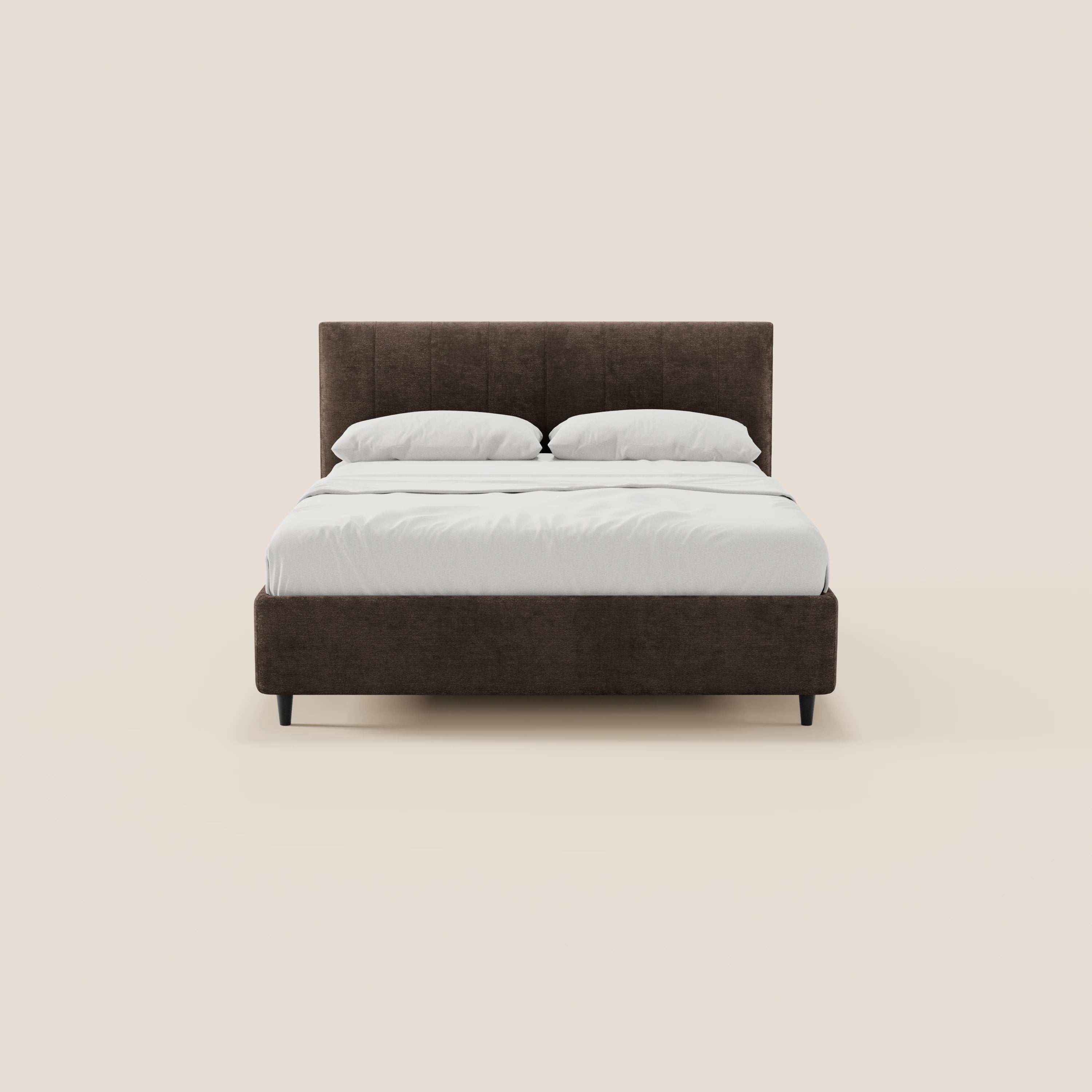 Vista frontale del letto imbottito con contenitore ONYX di Letti.store, caratterizzato da una testiera verticale marrone scuro in tessuto certificato Oeko-Tex®. Il letto è rifatto con cura con biancheria da letto bianca e due cuscini, su uno sfondo beige chiaro.
