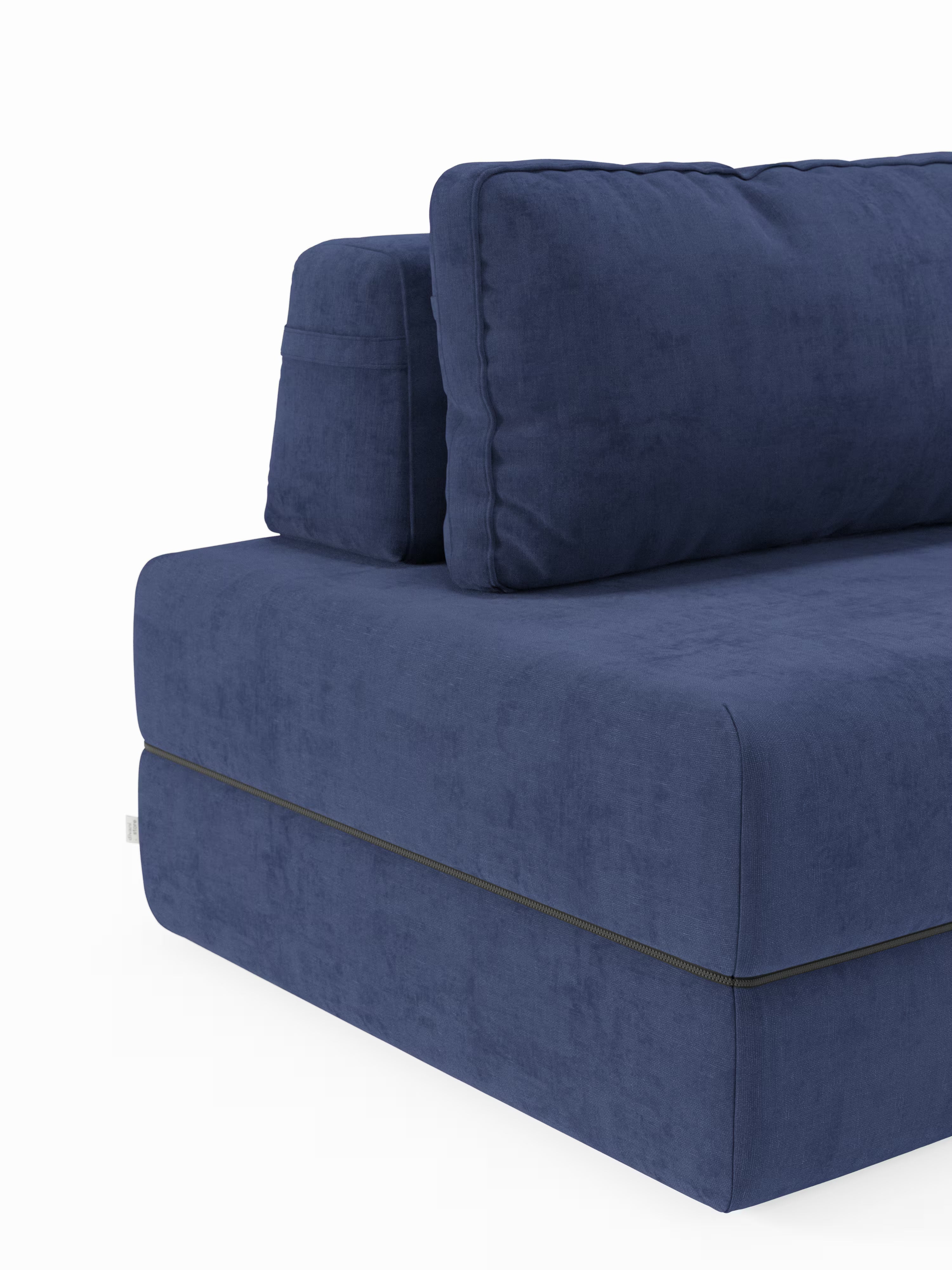 Un primo piano della poltrona letto Rift con materasso alto 22 cm e memory foam di Divani.Store ne mette in risalto il design contemporaneo e l’esclusivo tessuto T31 resistente alle macchie. L’immagine mostra il lato sinistro, con cuscini di seduta e schienale spessi e confortevoli, sostenuti da uno schienale mobile. Linee pulite, una superficie dalla trama delicata e una cucitura orizzontale vicino alla base riflettono la cura artigianale di questo moderno divano blu.