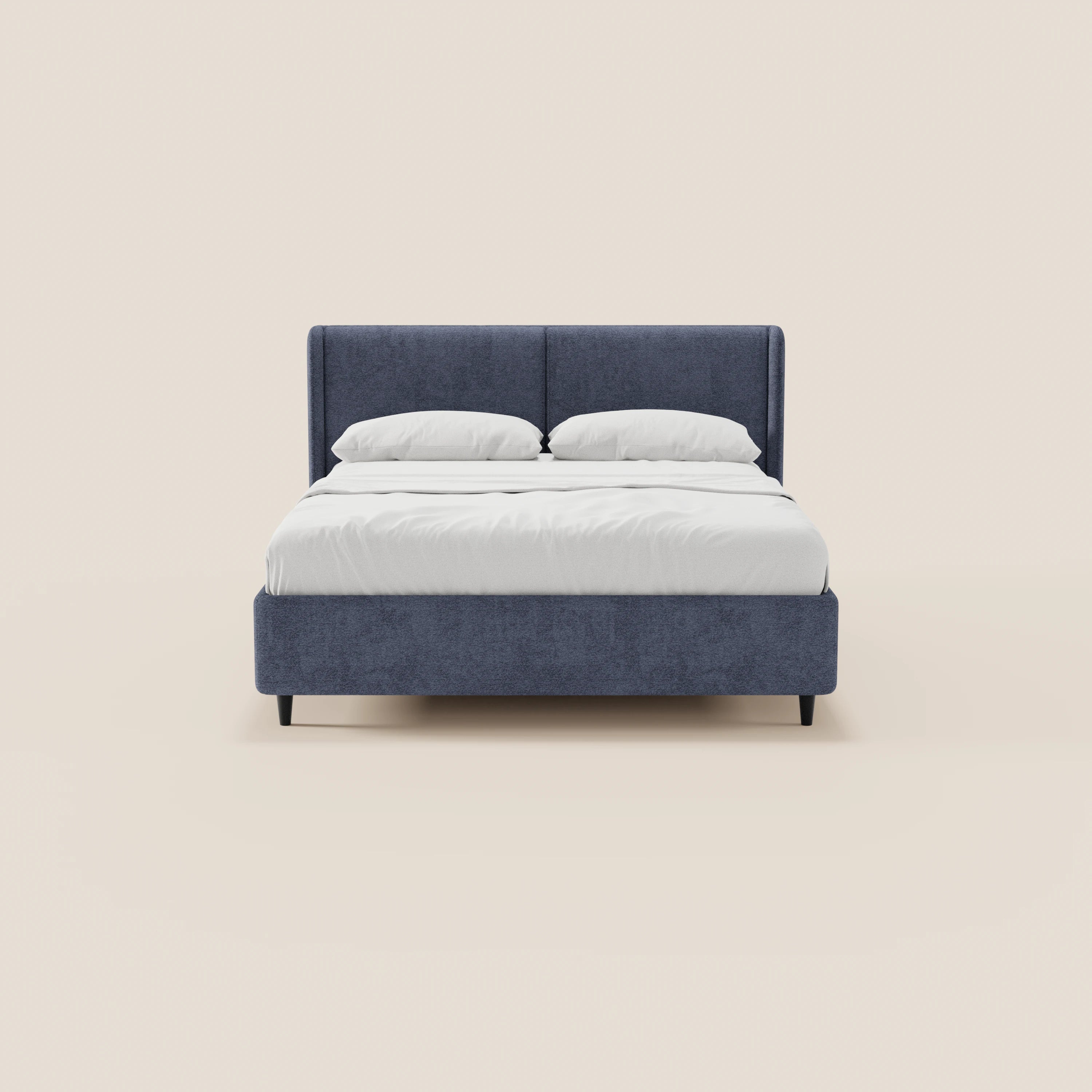 Una vista frontale del letto di design VALKIRIA di Letti.store, caratterizzato da una struttura rivestita in blu scuro certificata Oeko-Tex®, una testiera avvolgente con 2 cuscini imbottiti, biancheria da letto e cuscini bianchi, semplici gambe nere — il tutto su uno sfondo beige chiaro.