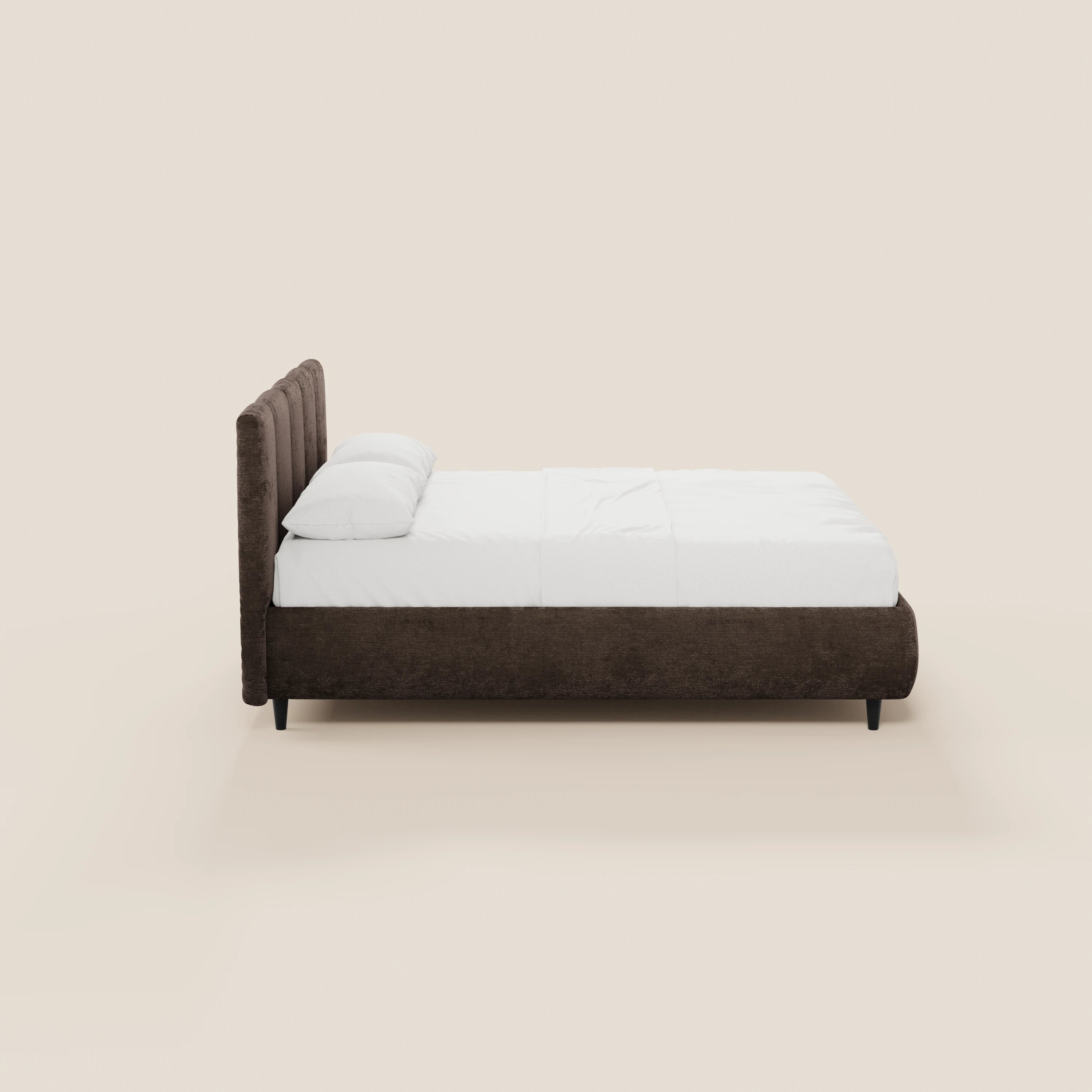 Il letto imbottito ARKAM di Letti.store, dotato di vano contenitore, testiera con lavorazione verticale e design shabby chic in tessuto Oeko-Tex®, è raffigurato di profilo con cornice marrone scuro, gambe basse nere e biancheria da letto bianca su uno sfondo beige chiaro.