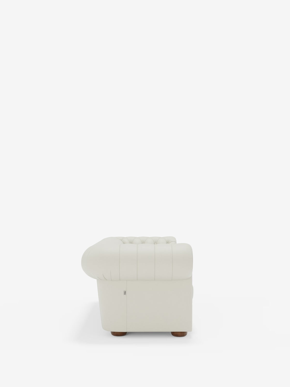 Vista laterale di una poltrona in pelle bianca trapuntata con braccioli arrotondati, cuciture verticali e gambe corte in legno — che richiama il classico stile Chesterfield — su uno sfondo bianco a tinta unita. Il modello Chester – Divano Chesterfield in vera pelle spessorata a 2 e 3 posti di Divani.Store è un esempio di squisita maestria artigianale italiana ed eleganza senza tempo.