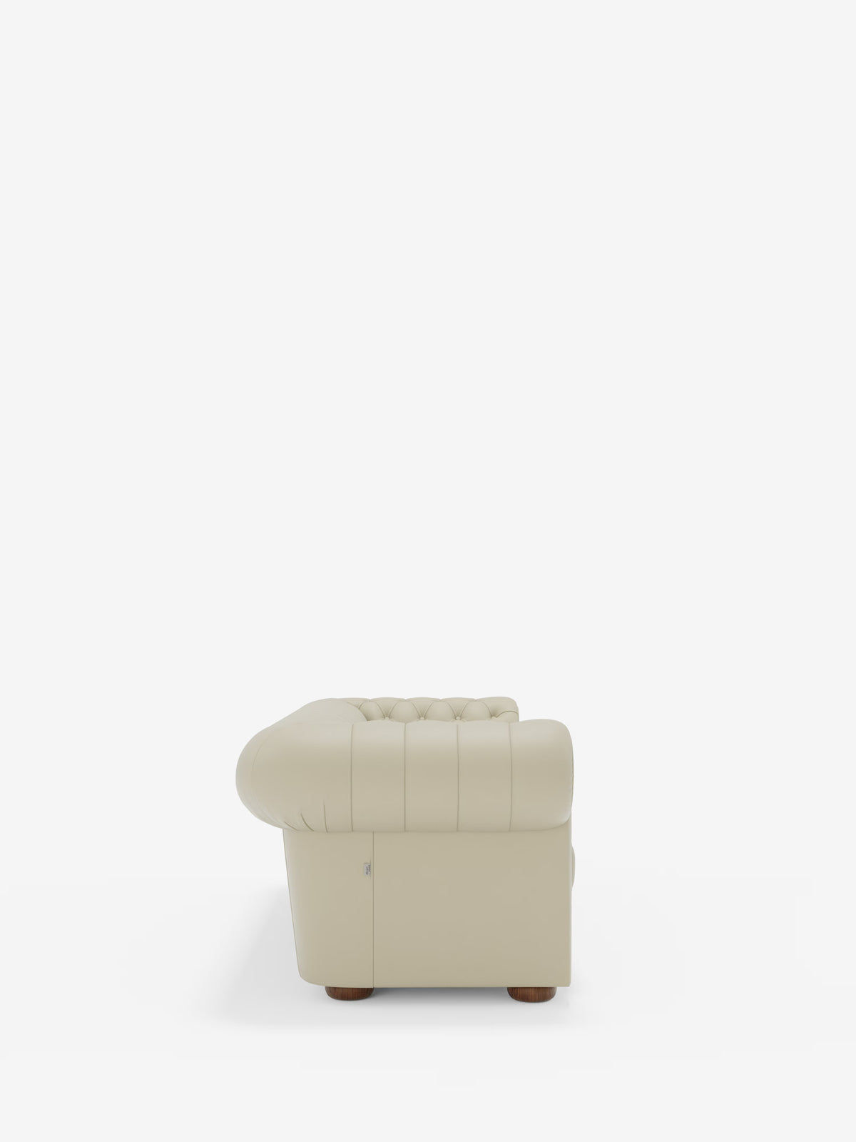 Vista laterale del divano Chester 4 Posti 3 sedute in vera pelle – Chesterfield capitonné artigianale di Divani.Store, caratterizzato da un rivestimento in vera pelle beige con dettagli capitonné e braccioli e schienale arrotondati, poggiato su piccoli piedini rotondi in legno. Lo sfondo bianco a tinta unita mette in risalto la forma artigianale e la raffinata lavorazione di questo divano Chesterfield.