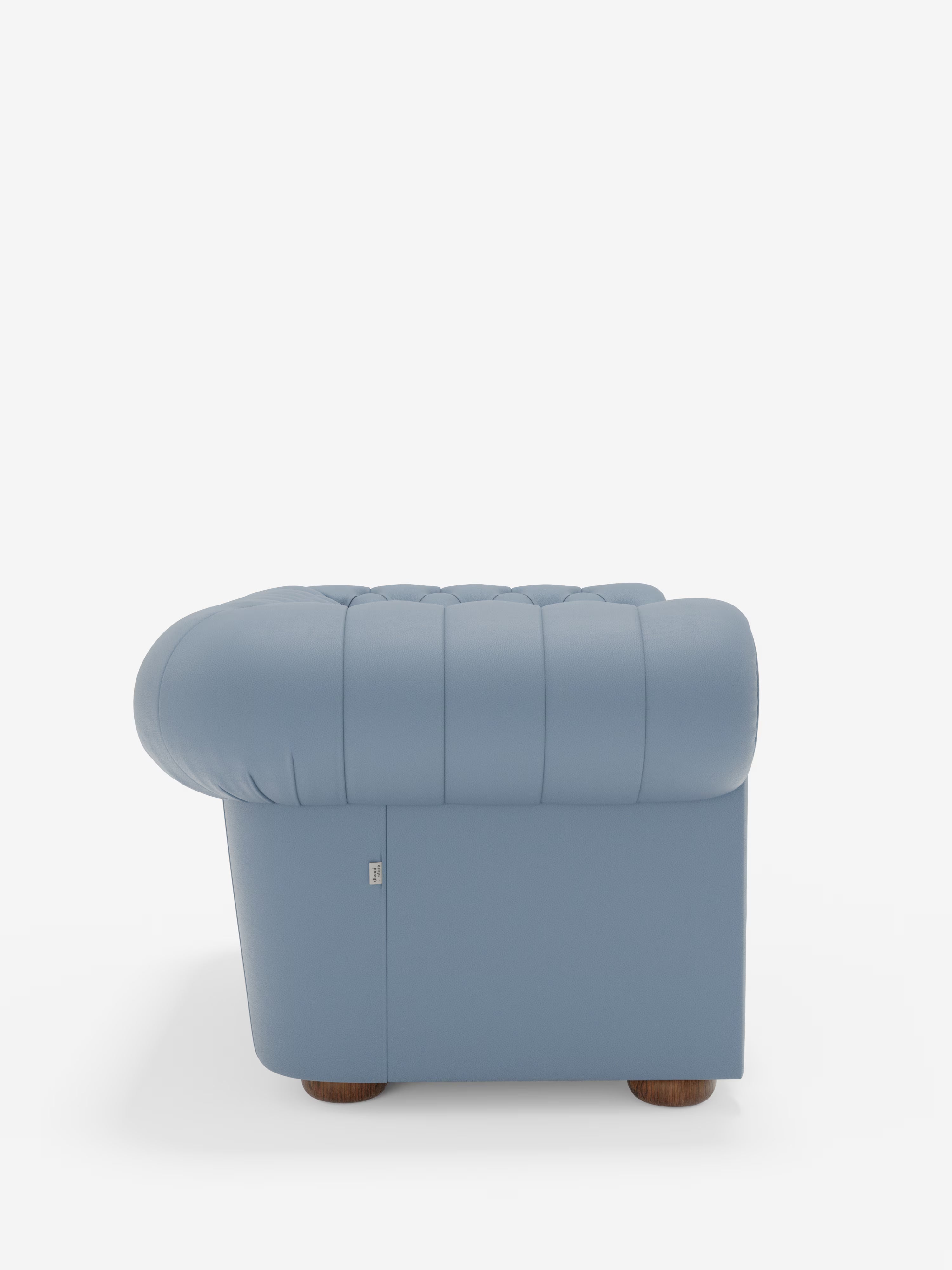 Una “Chester Poltrona in vera pelle spessorata con capitonné artigianale” di Divani.Store, di colore azzurro, è raffigurata di profilo e presenta morbidi braccioli arrotondati e uno schienale impreziosito da eleganti cuciture verticali. Ispirata alla raffinata poltrona Chester classica, questa lussuosa poltrona poggia su gambe corte e rotonde in legno ed è messa in risalto da uno sfondo bianco a tinta unita.