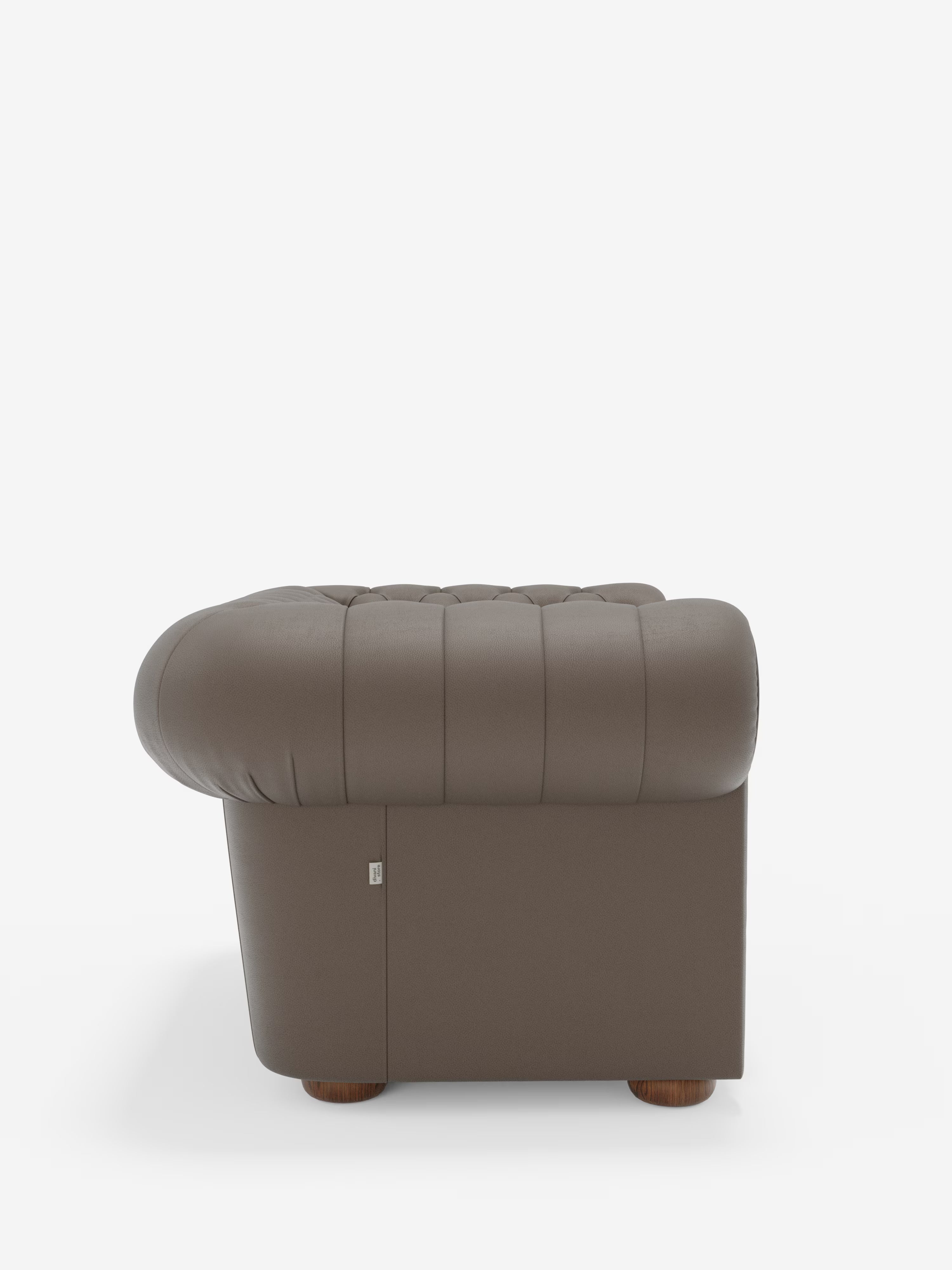 Una vista laterale della poltrona Chester in vera pelle spessorata con capitonné artigianale di Divani.Il prodotto si presenta con la sua ricca tonalità marrone e il design capitonné che richiama lo stile classico Chester, caratterizzato da schienale e braccioli arrotondati e imbottiti, sostenuti da gambe corte e rotonde in legno — un vero e proprio elemento d’arredo di lusso — che risalta su uno sfondo bianco a tinta unita.