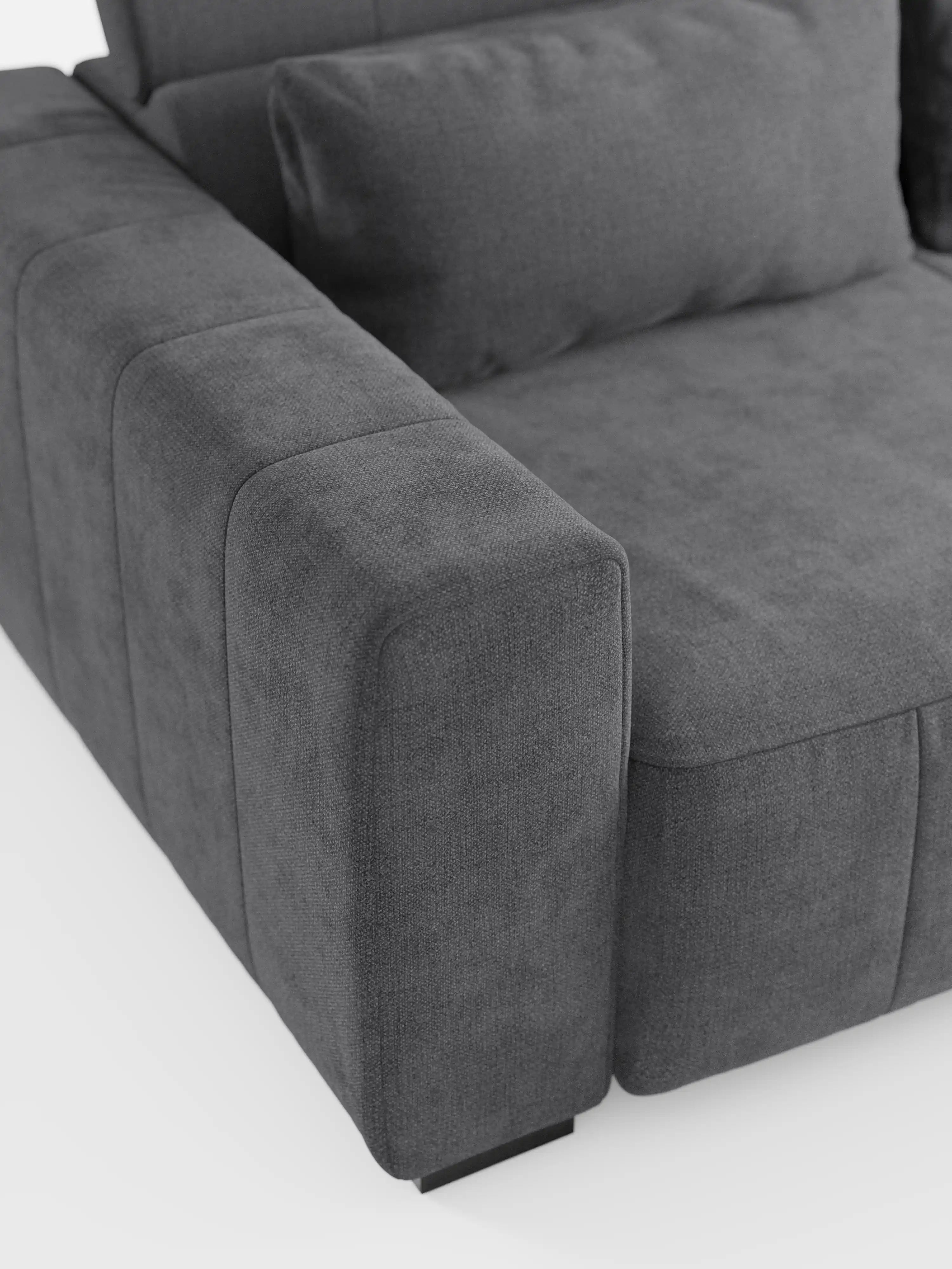 Primo piano del divano Doric a 3 posti di Divani.Store, realizzato in tessuto T23 grigio scuro smacchiabile, caratterizzato da cuciture a vista, un ampio bracciolo e un cuscino dello schienale con poggiatesta reclinabile. Il design presenta sedute allungabili tramite meccanismo elettrico relax e si inserisce in un contesto luminoso, che ne esalta le linee pulite e minimaliste e la morbida trama del rivestimento.