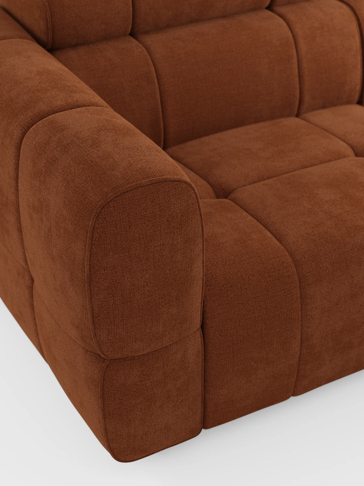 Un primo piano del divano modulare Giotto a 4 posti con poggiatesta reclinabili e funzione relax elettrica opzionale, rivestito in tessuto smacchiabile T23, caratterizzato da un tessuto testurizzato color ruggine, morbidi bordi arrotondati e dettagli trapuntati su uno sfondo bianco a tinta unita.