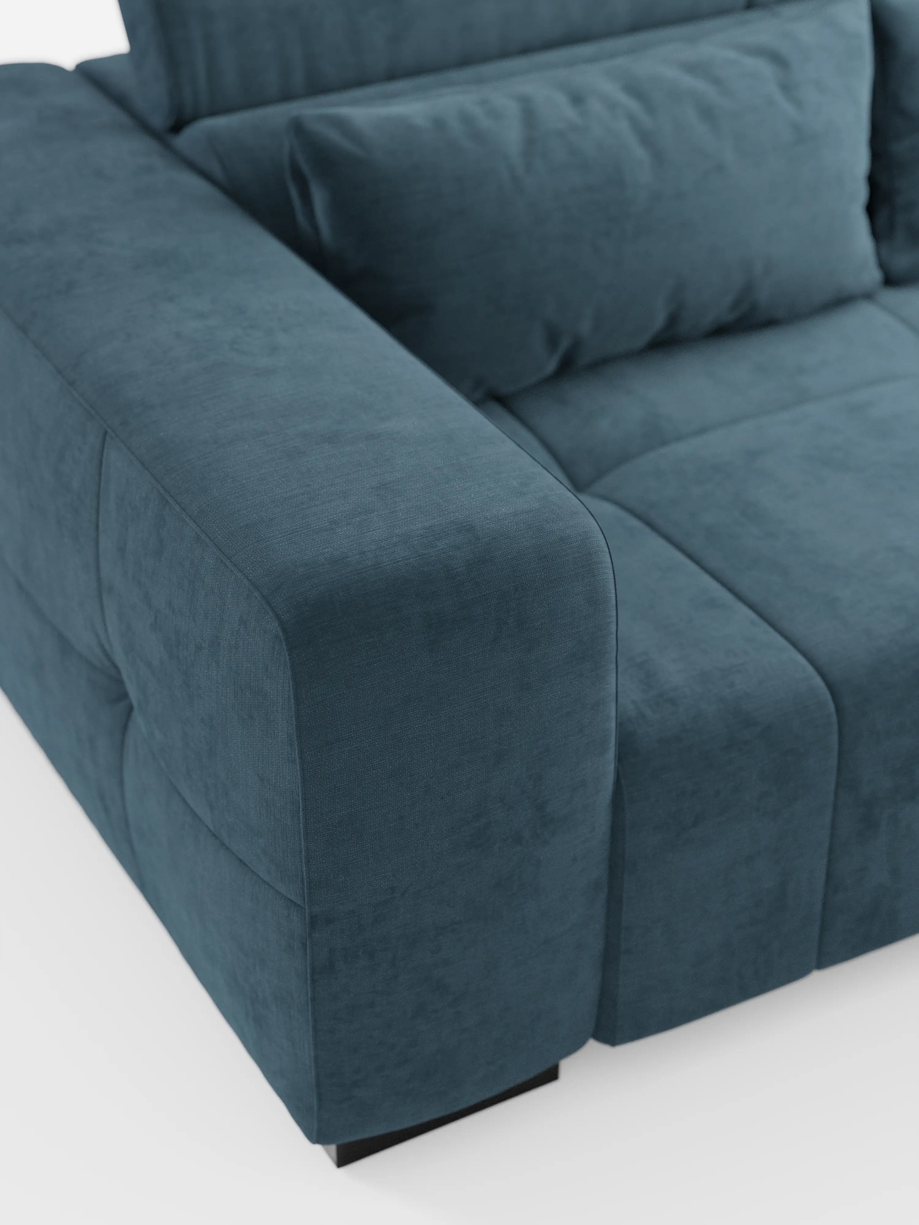 Primo piano del divano Monarch con funzione relax elettrica per l’allungamento delle sedute e poggiatesta reclinabile, rivestito in morbido tessuto smacchiabile T31 di Divani.Store, che mette in risalto il suo moderno rivestimento in velluto blu-verde acqua, i braccioli generosi e il cuscino imbottito. Questo divano contemporaneo presenta una silhouette squadrata e lussuosa con cuciture a vista e poggia su gambe corte nere su uno sfondo bianco a tinta unita.