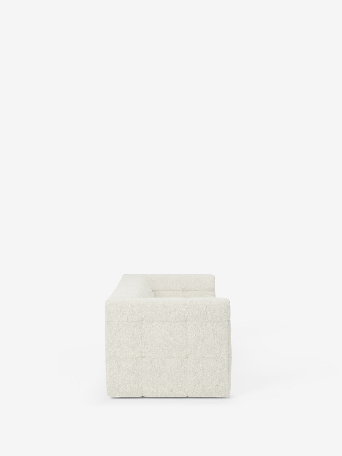 Vista laterale del divano modulare Mosaic a 3 e 4 posti in bouclé di Divani.Store, caratterizzato da una silhouette moderna e minimalista con una forma squadrata e cuciture capitonné a griglia. Il tessuto T21 bianco sporco e resistente alle macchie ne esalta le linee pulite e la consistenza morbida, con il design modulare che spicca su uno sfondo bianco.