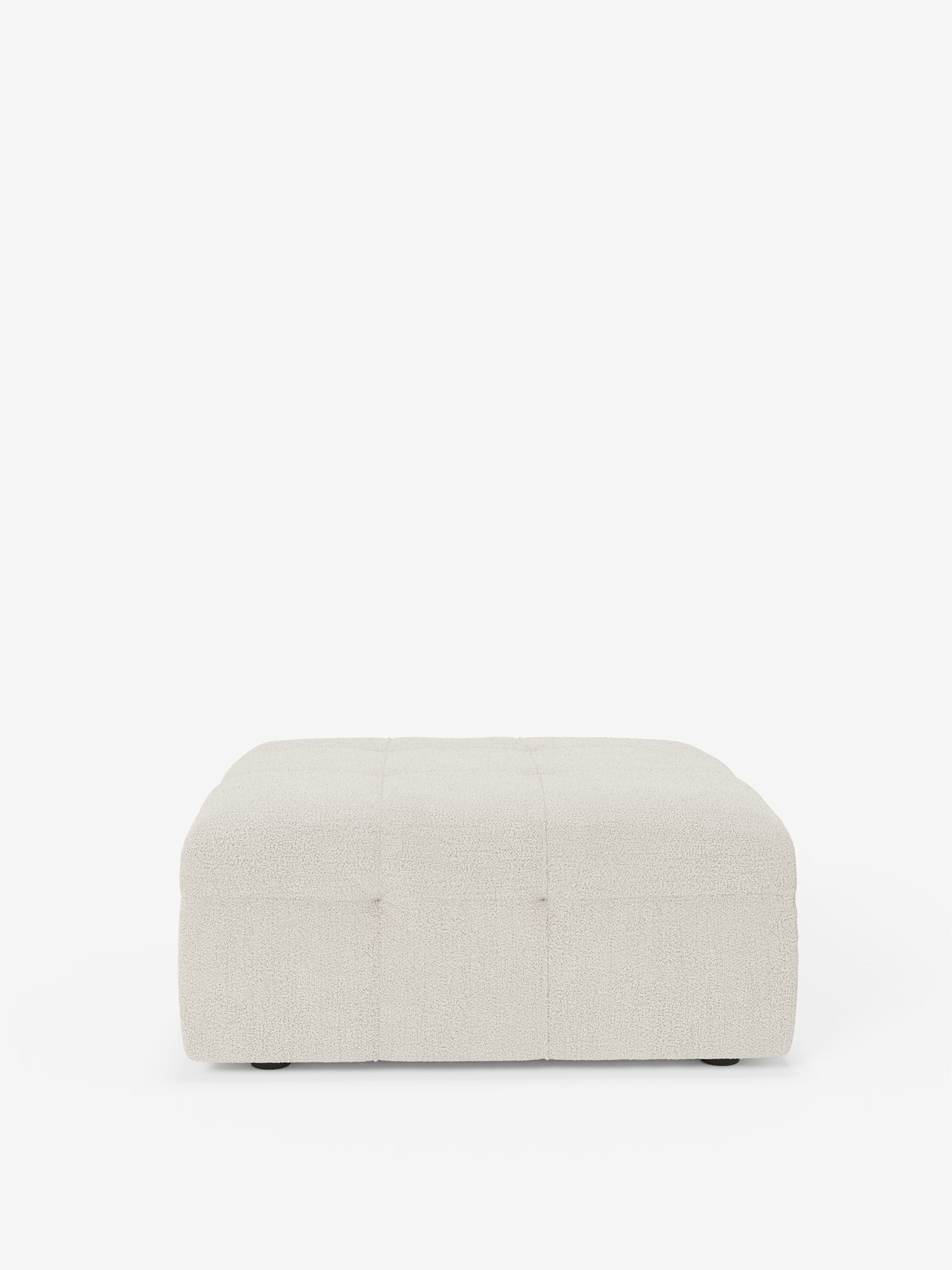 Il pouf e modulo Mosaic in bouclé di Divani.Store è un pouf quadrato dal profilo ribassato che misura 96x77 cm. Rivestito in tessuto bouclé T21 testurizzato, color bianco sporco e resistente alle macchie, presenta un elegante motivo capitonné (imbottito) sulla superficie superiore e poggia su discreti piedini neri, qui raffigurato su uno sfondo bianco a tinta unita.